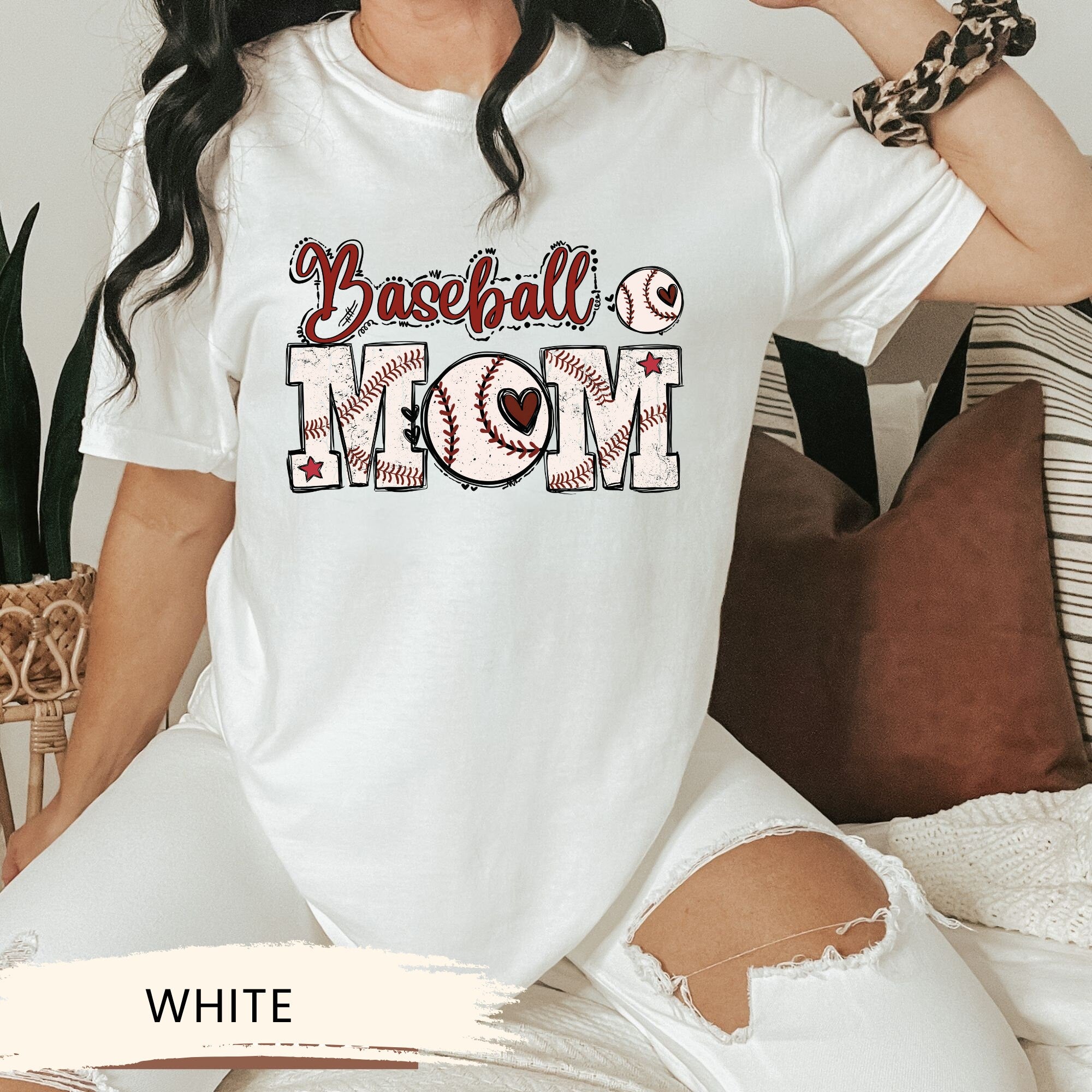 a woman sitting on a couch wearing a baseball mom shirt