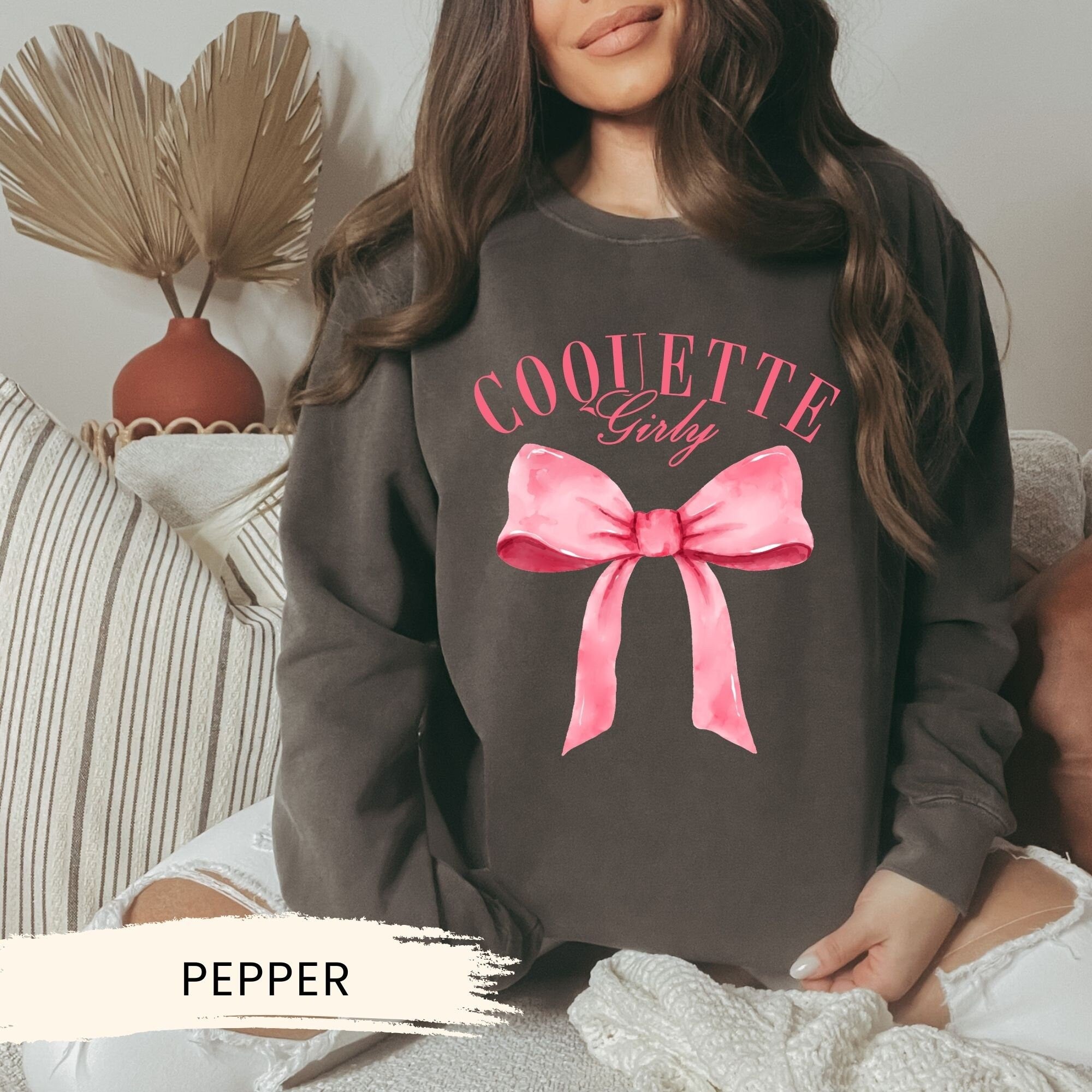 a woman wearing a sweatshirt with a pink bow on it