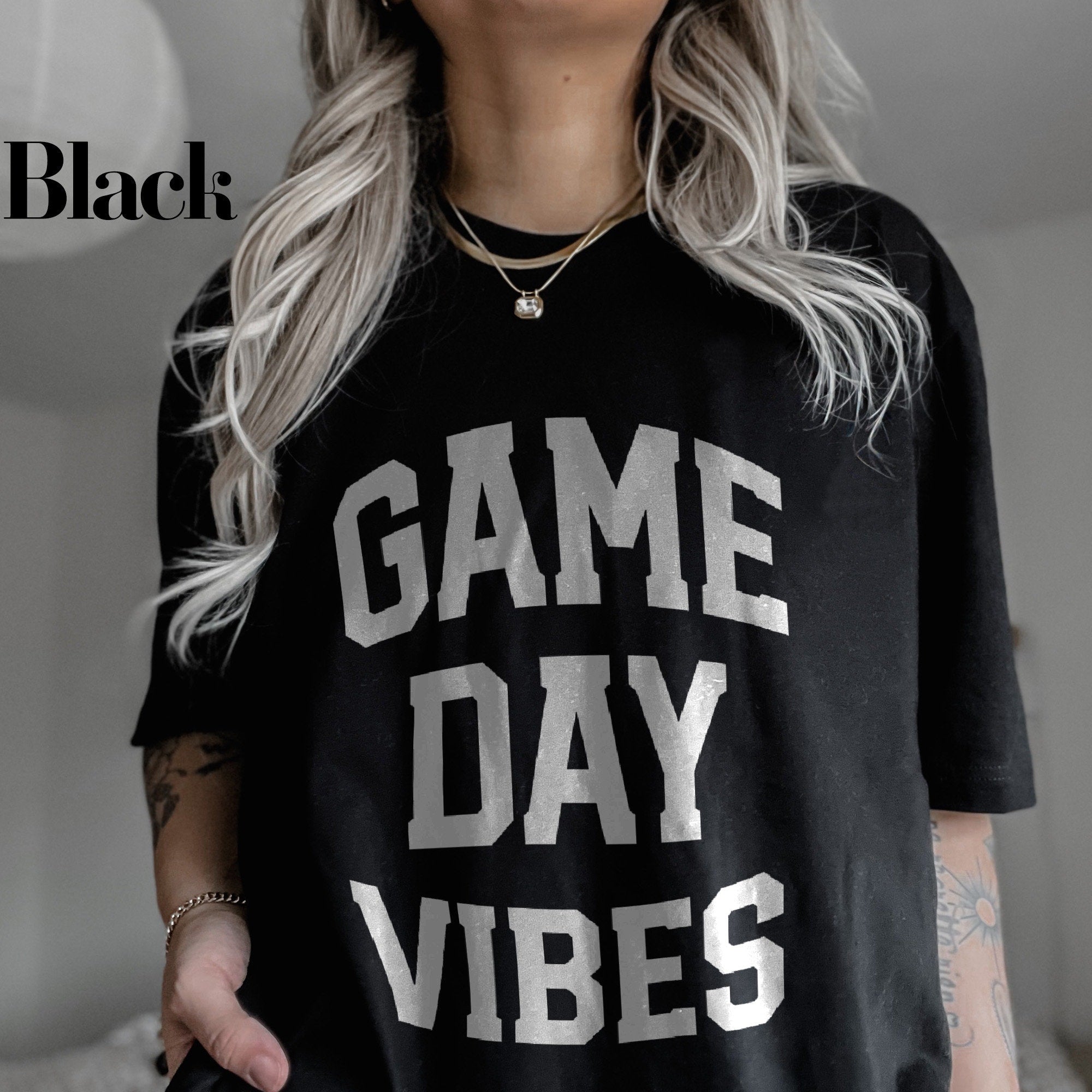 a woman wearing a black game day vibes shirt