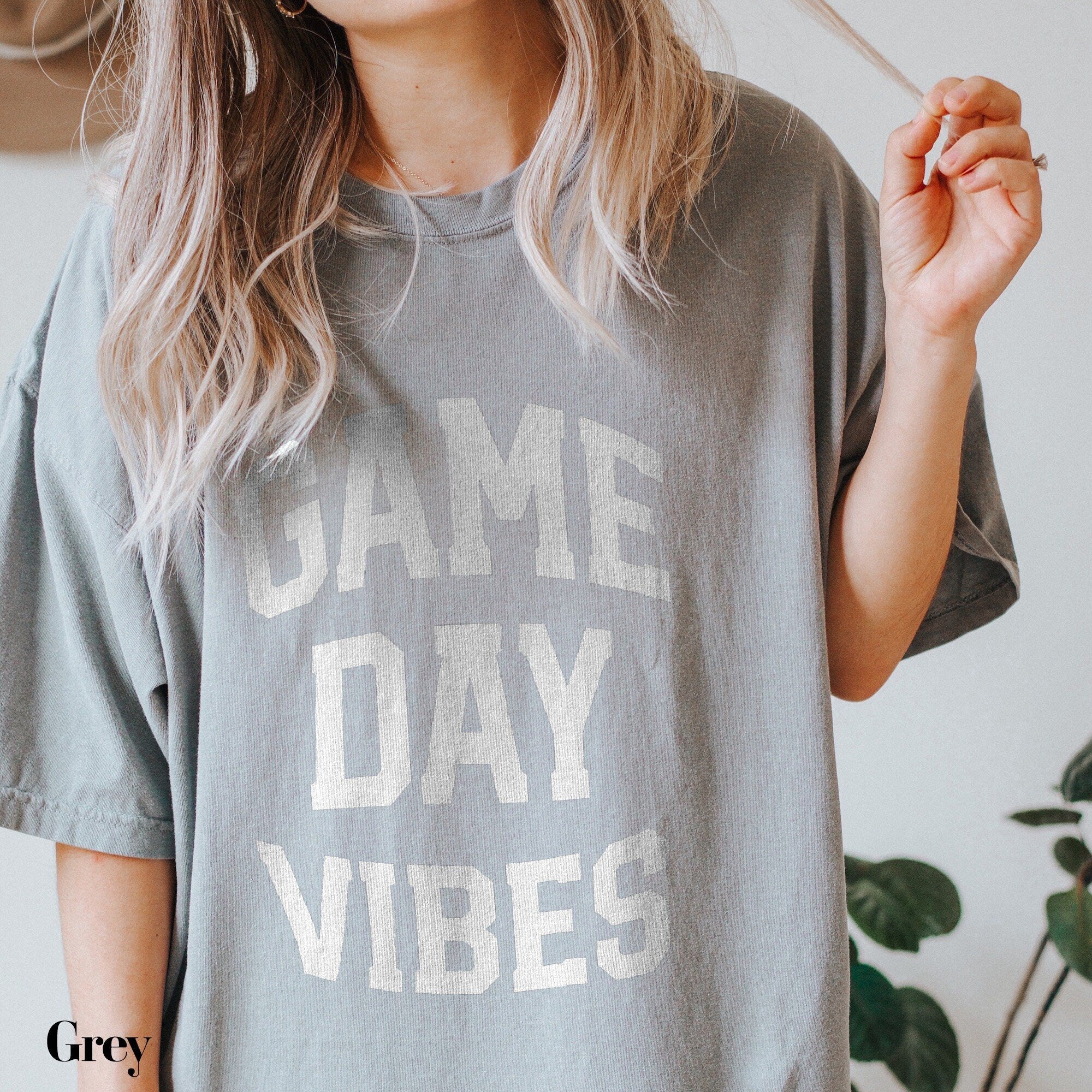 a woman holding a cigarette and wearing a t - shirt that says james day vibe