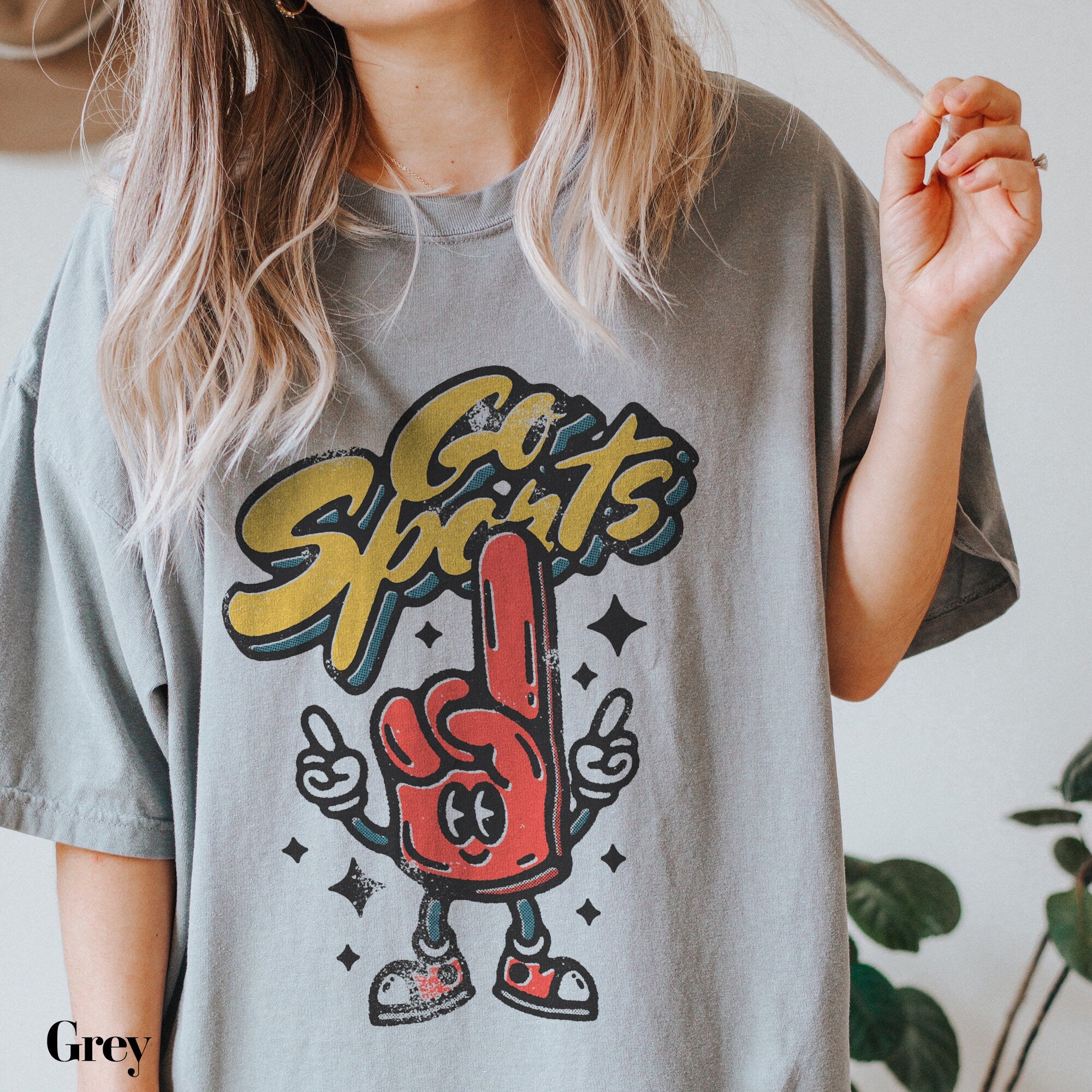 a woman holding a cigarette and wearing a gray shirt