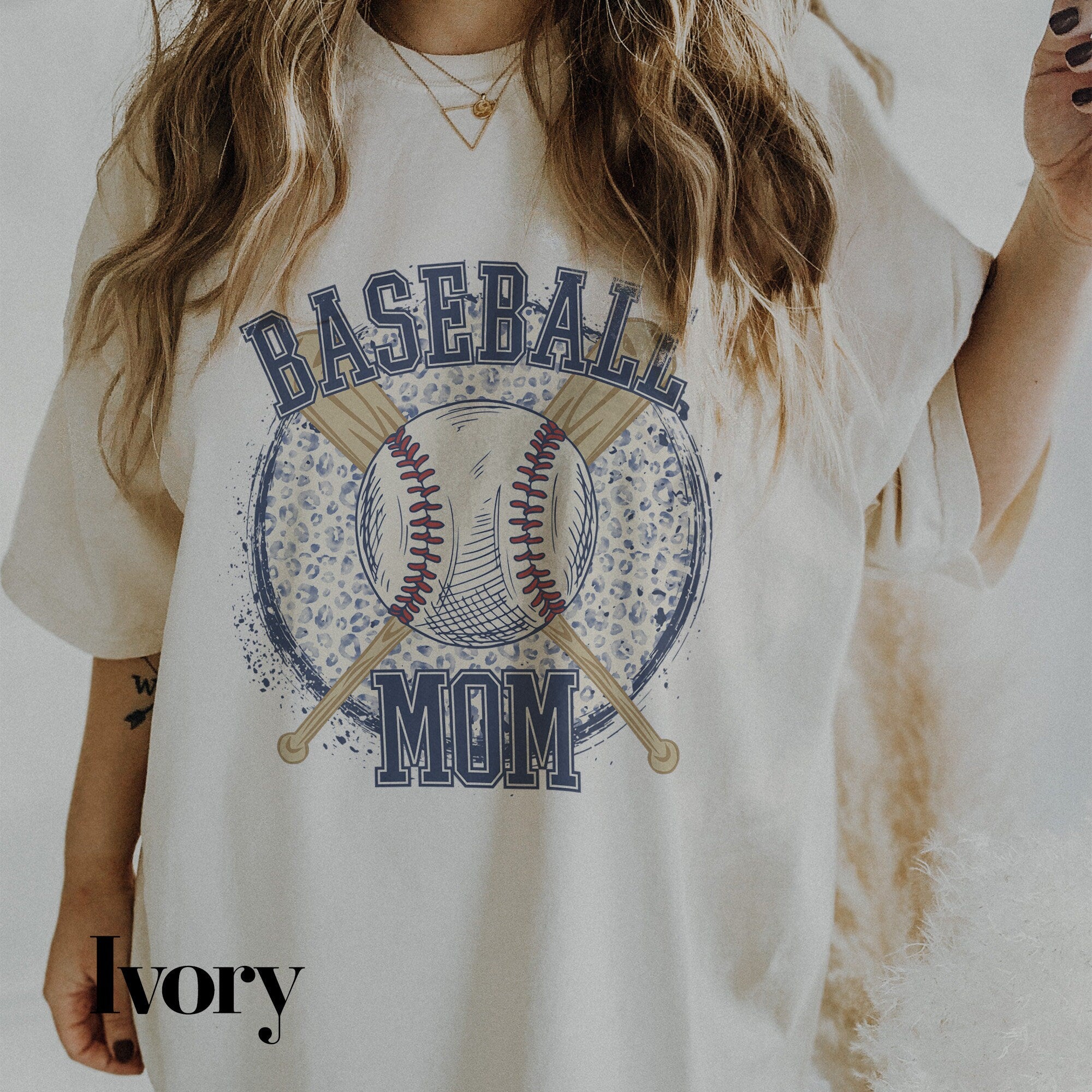 a woman wearing a baseball mom shirt holding a baseball bat