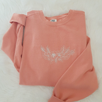 a pink sweatshirt with a flower embroidered on it