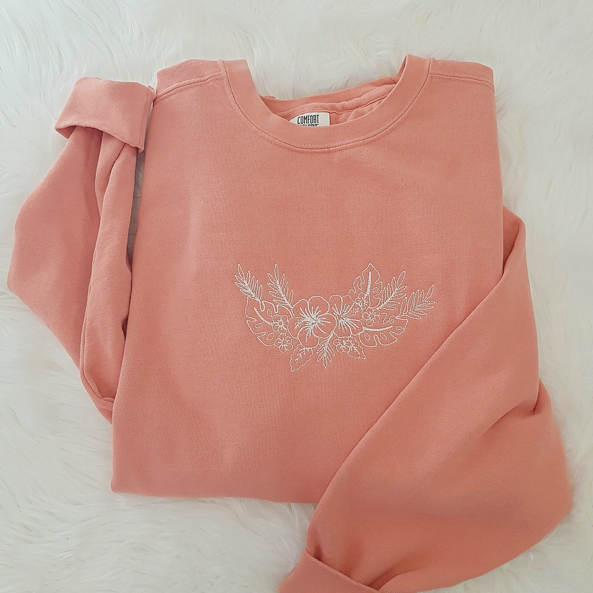 a pink sweatshirt with a flower embroidered on it