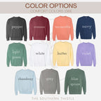 a collection of 12 different colored sweatshirts, each with a unique color and design. The sweatshirts are arranged in a grid format, with four rows and three columns. The colors of the sweatshirts are pepper, burgundy, terracotta, navy, light green, white, yellow, butter, violet, chambry, grey, blue, and blue sprig. The text above the image reads "COLOR OPTIONS" and "COMFORT COLORS 1566".