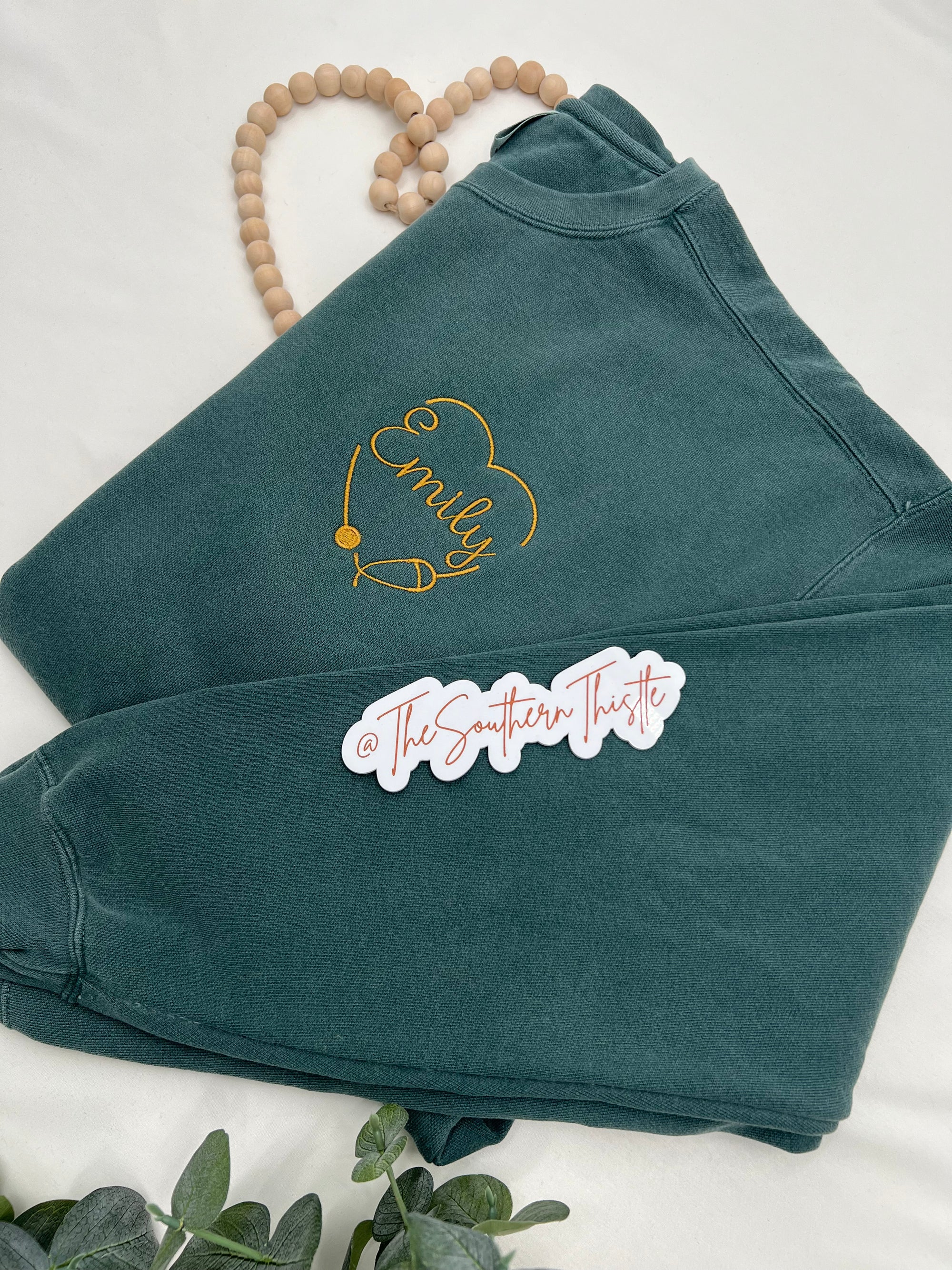 a close up of a shirt on a bed with a plant