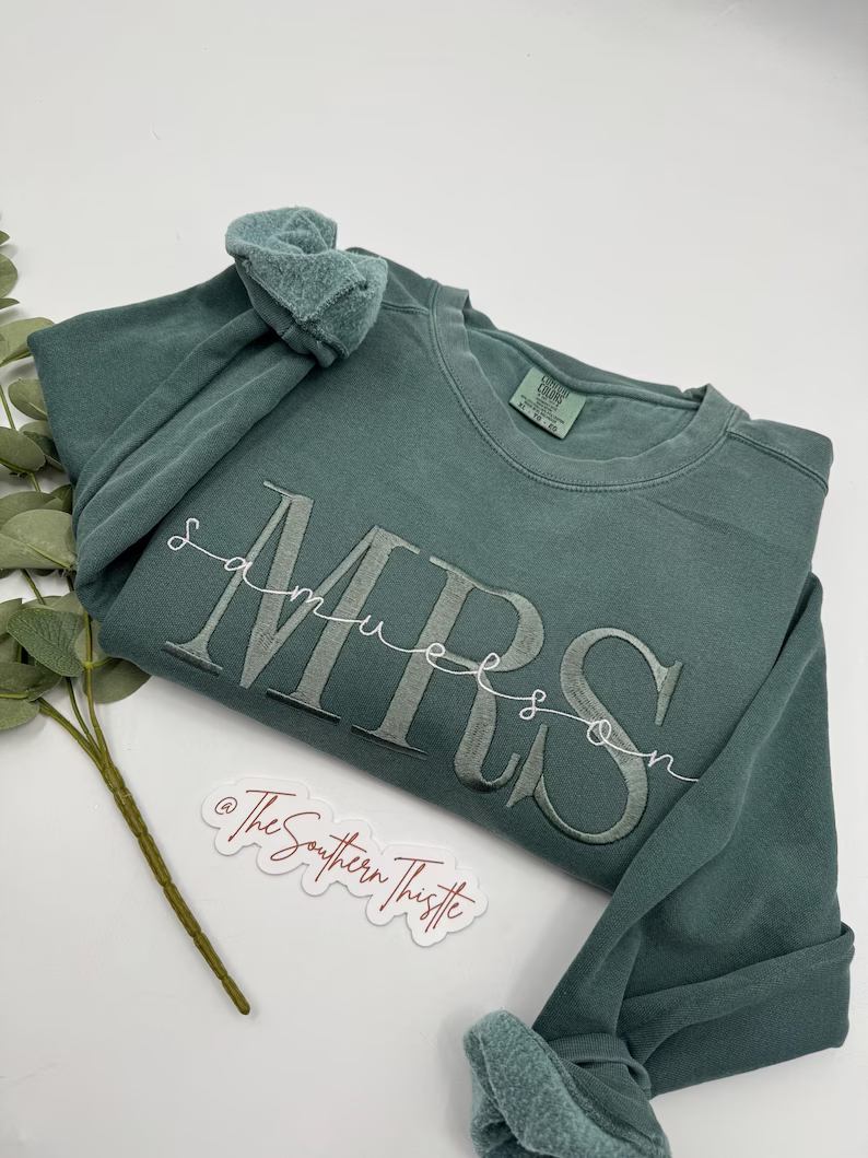 A green long-sleeved shirt with the text "Samuelson" printed on it, along with a small white sticker that says "@TheSouthernThistle".