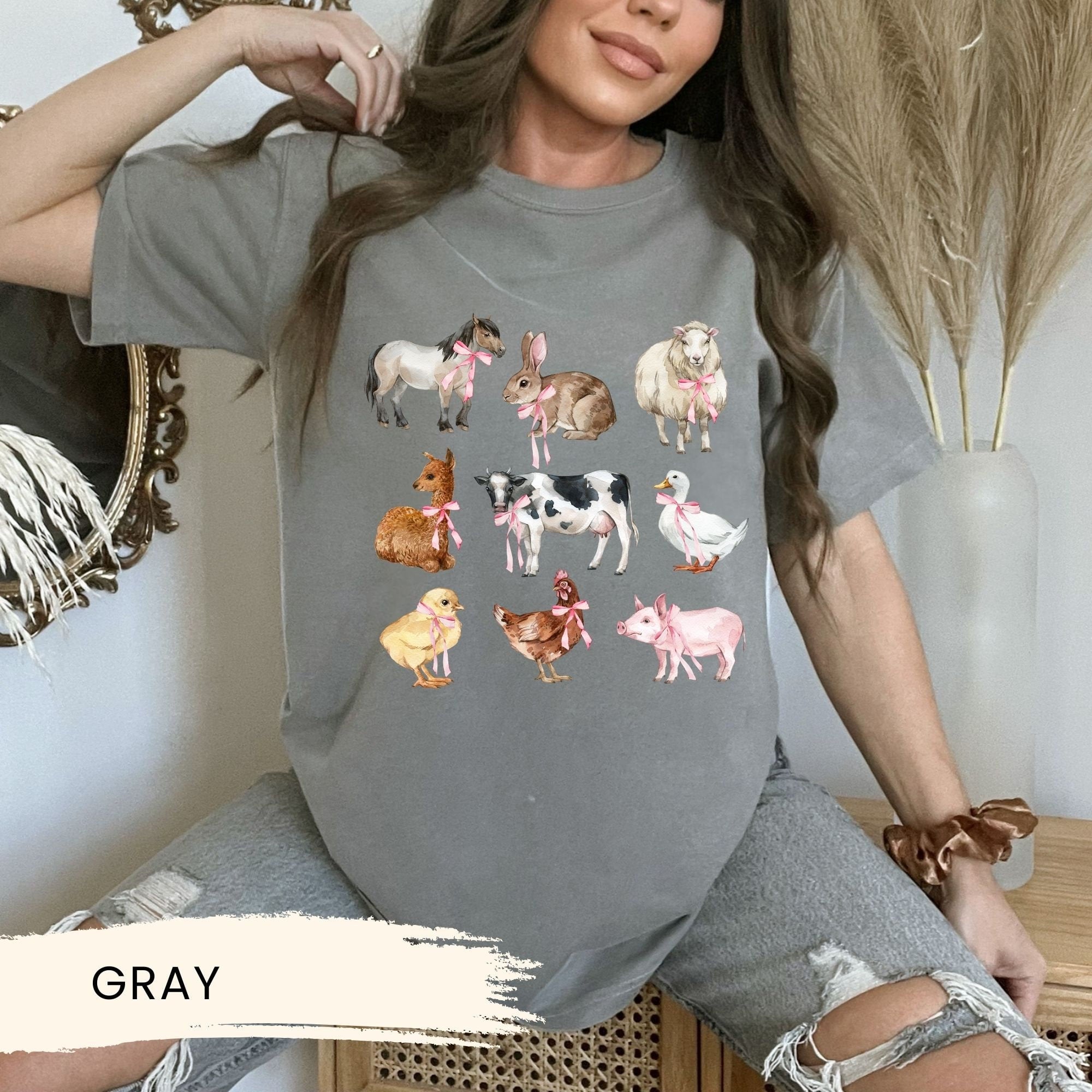 a woman wearing a gray shirt with farm animals on it