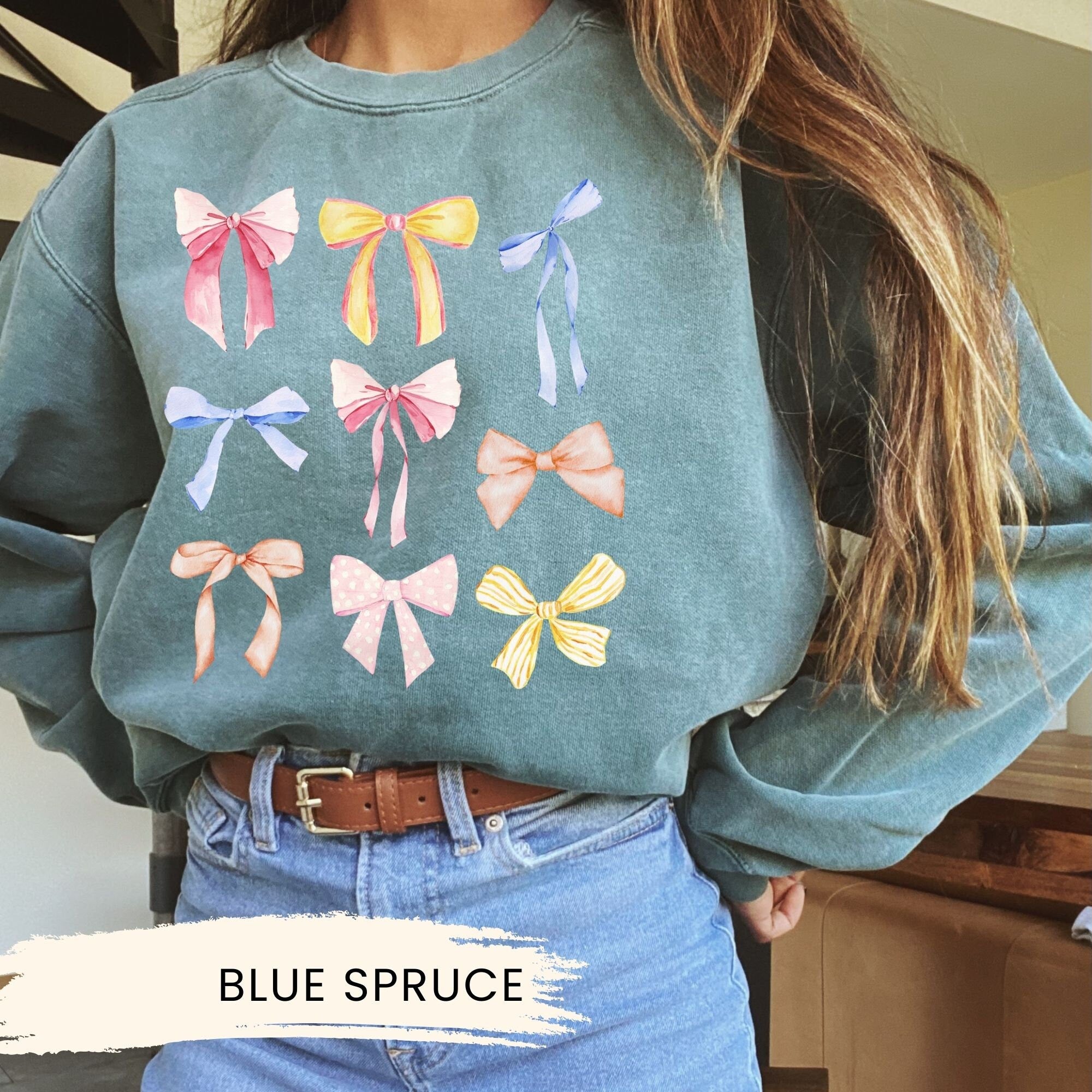 a woman wearing a blue sweater with bows on it