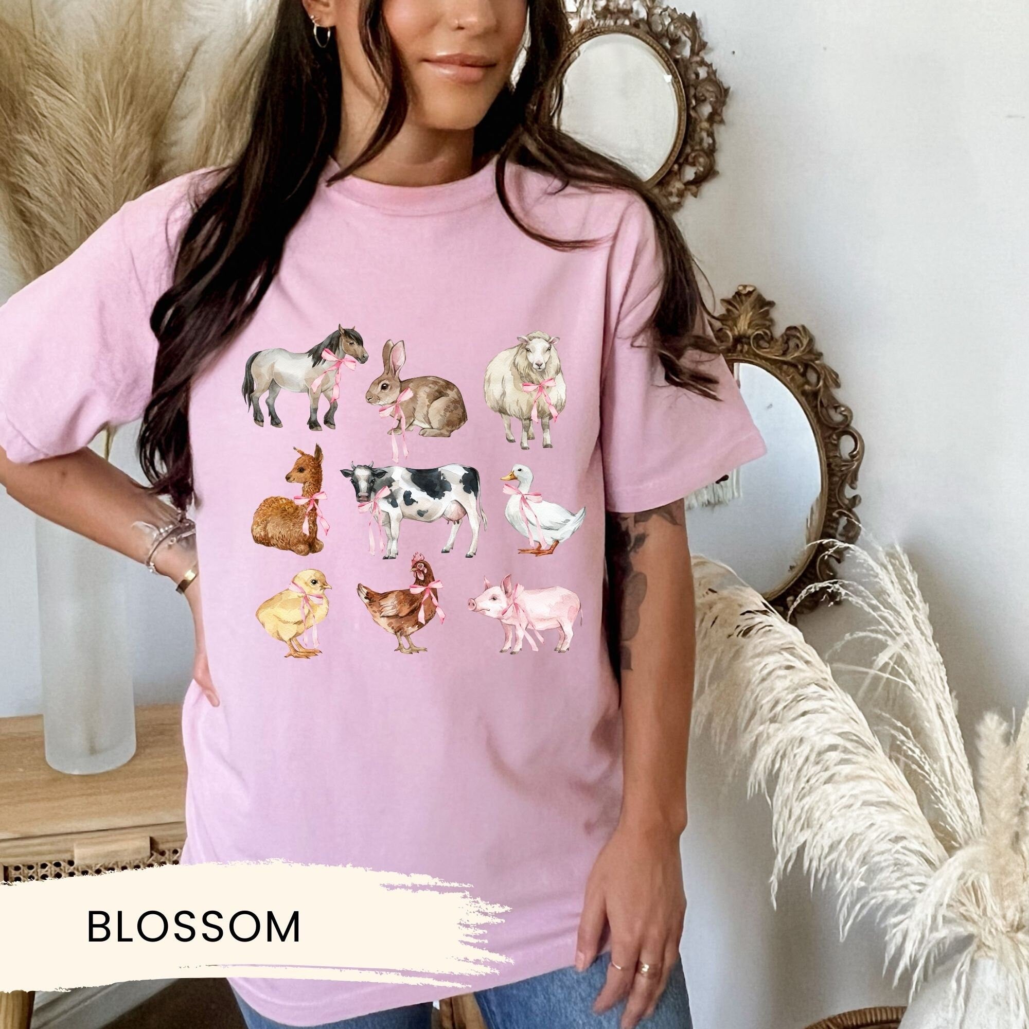 a woman wearing a pink shirt with farm animals on it