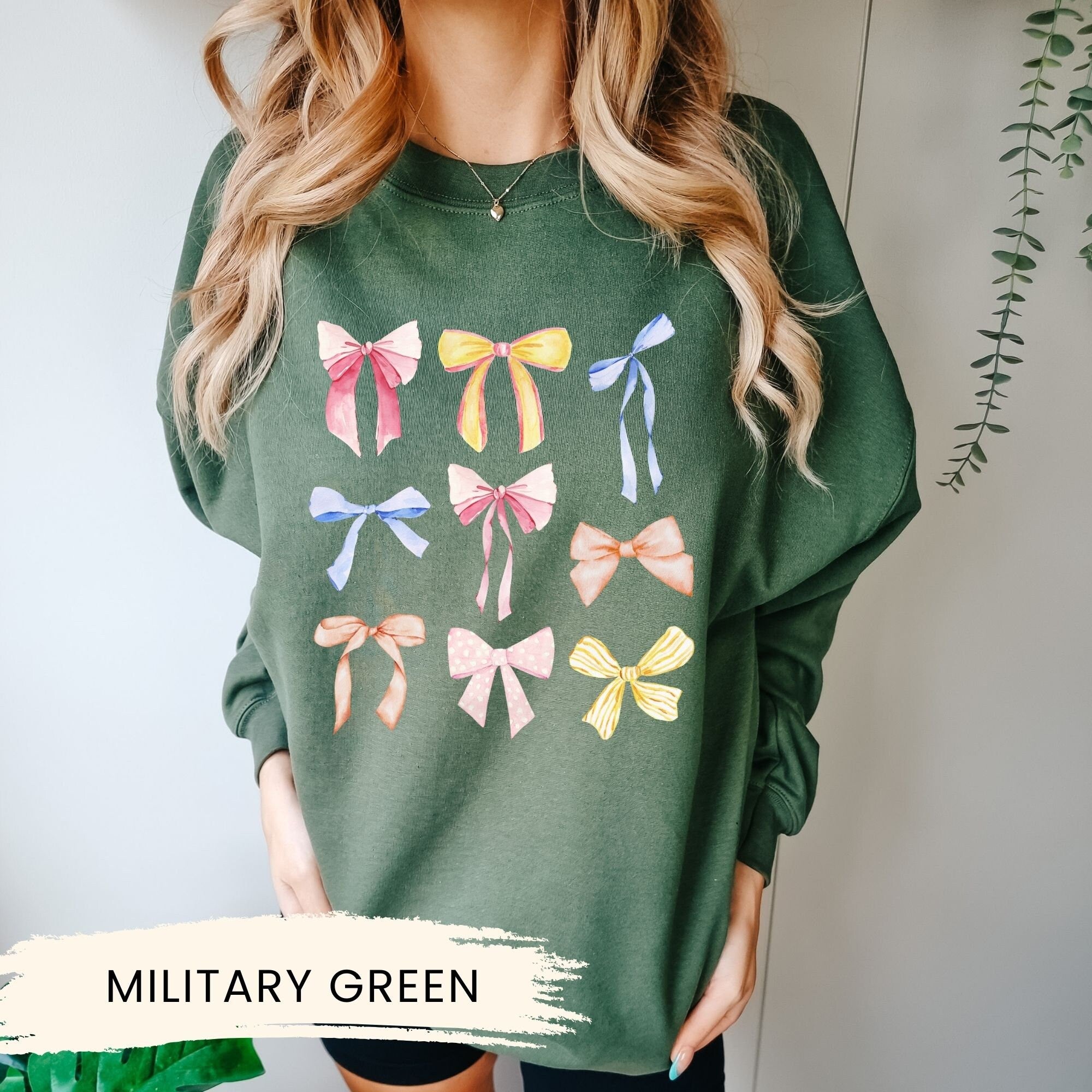 a woman wearing a military green sweater with bows on it