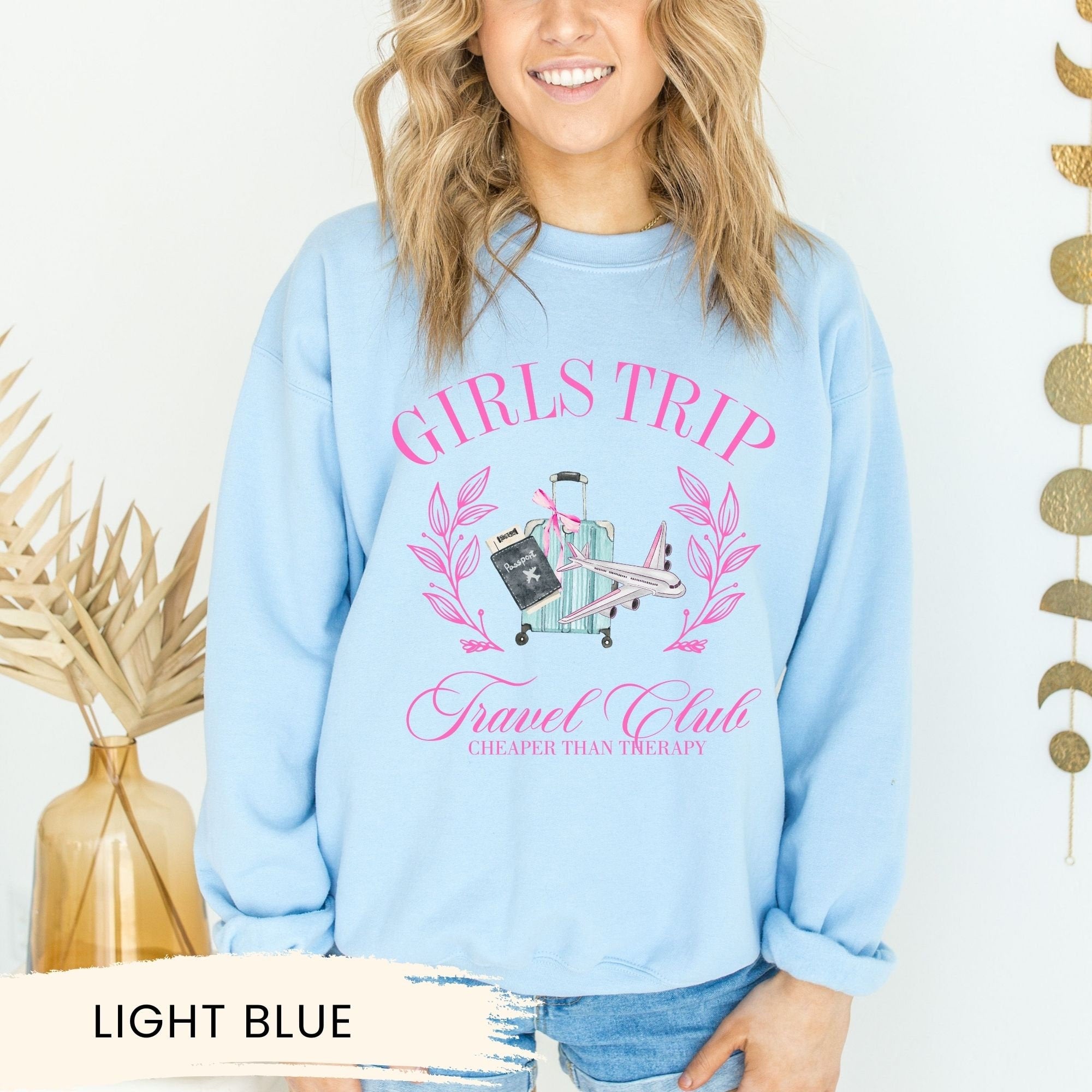 a woman wearing a light blue sweatshirt with the words girls trip on it