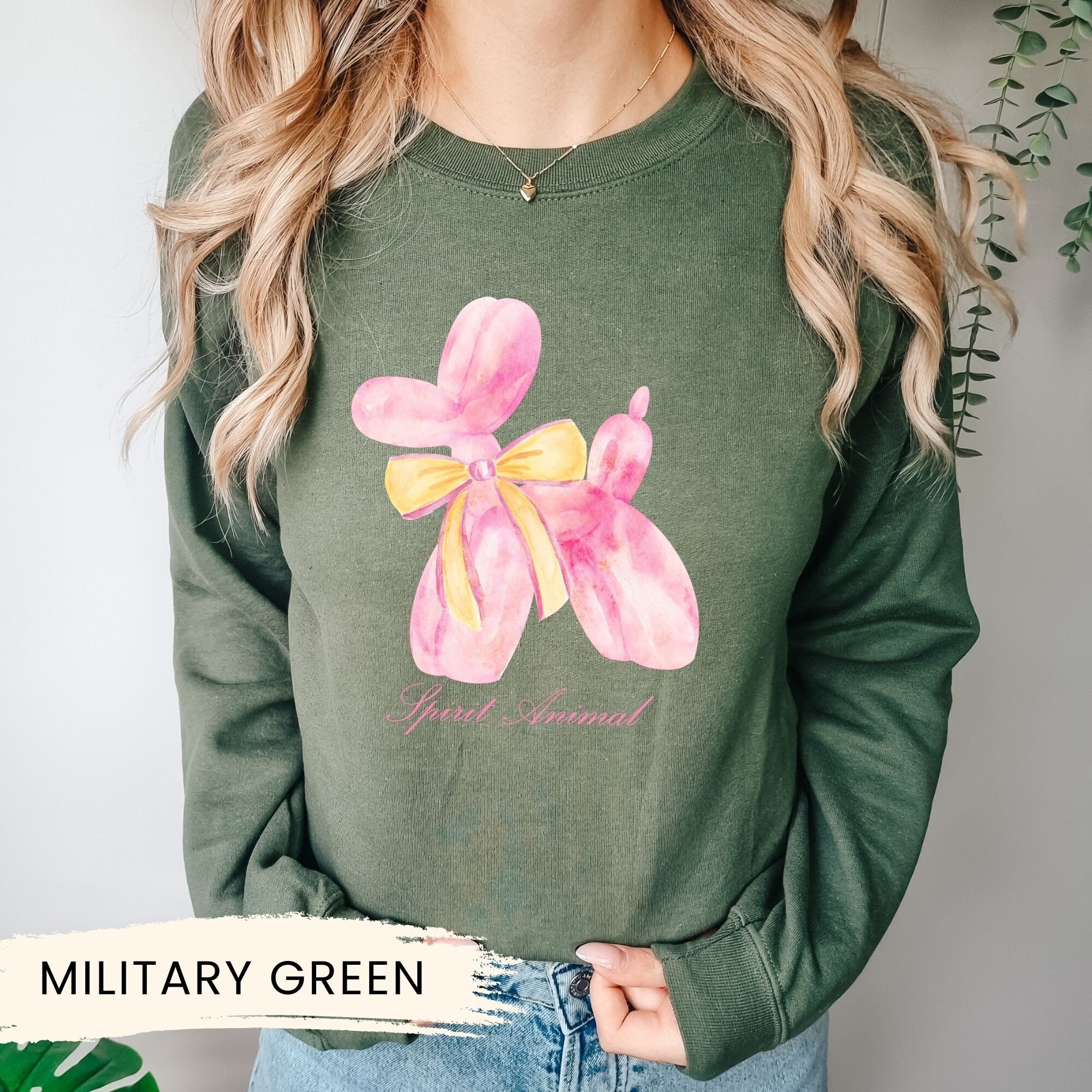 a woman wearing a military green sweatshirt with a pink flower on it