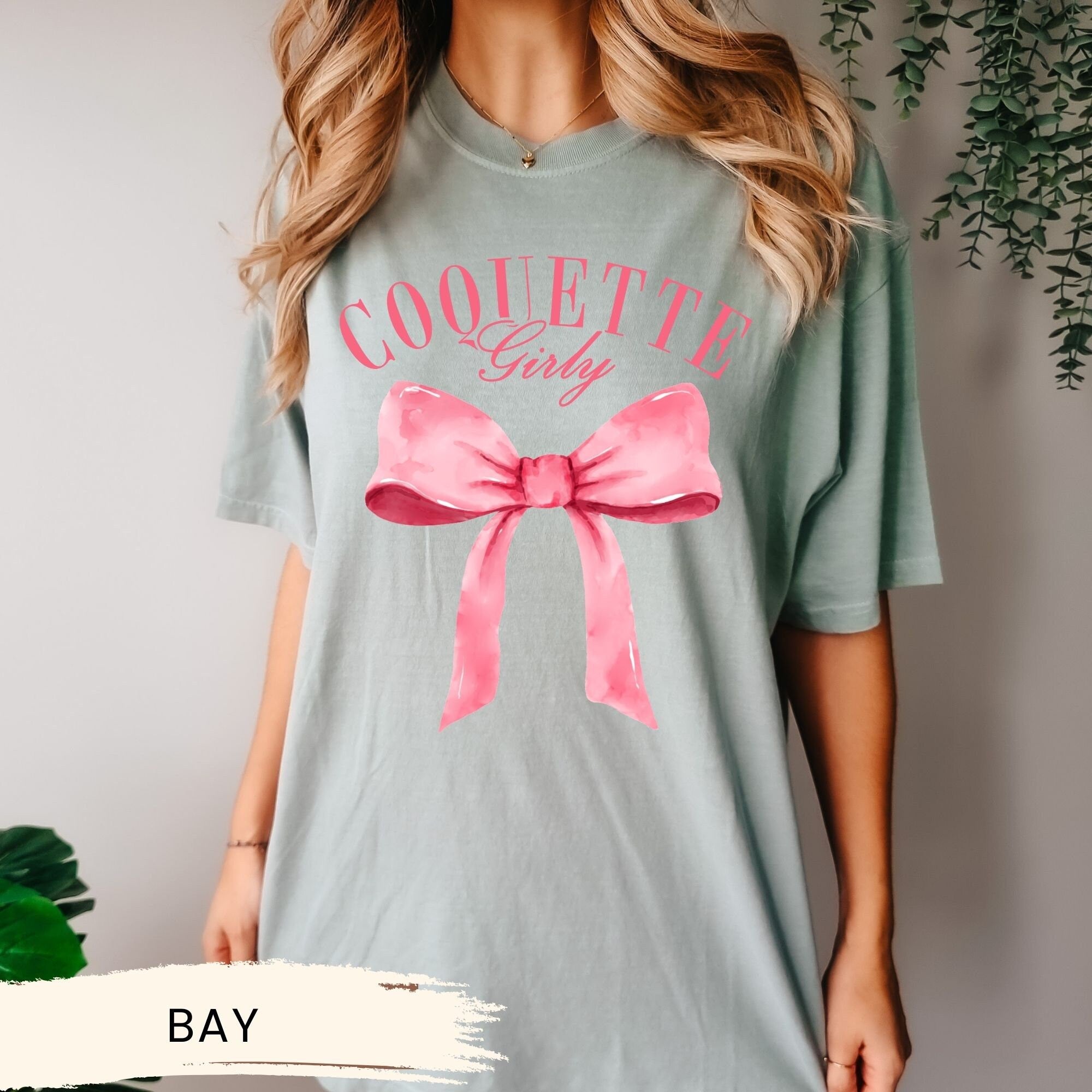 a woman wearing a t - shirt with a pink bow on it