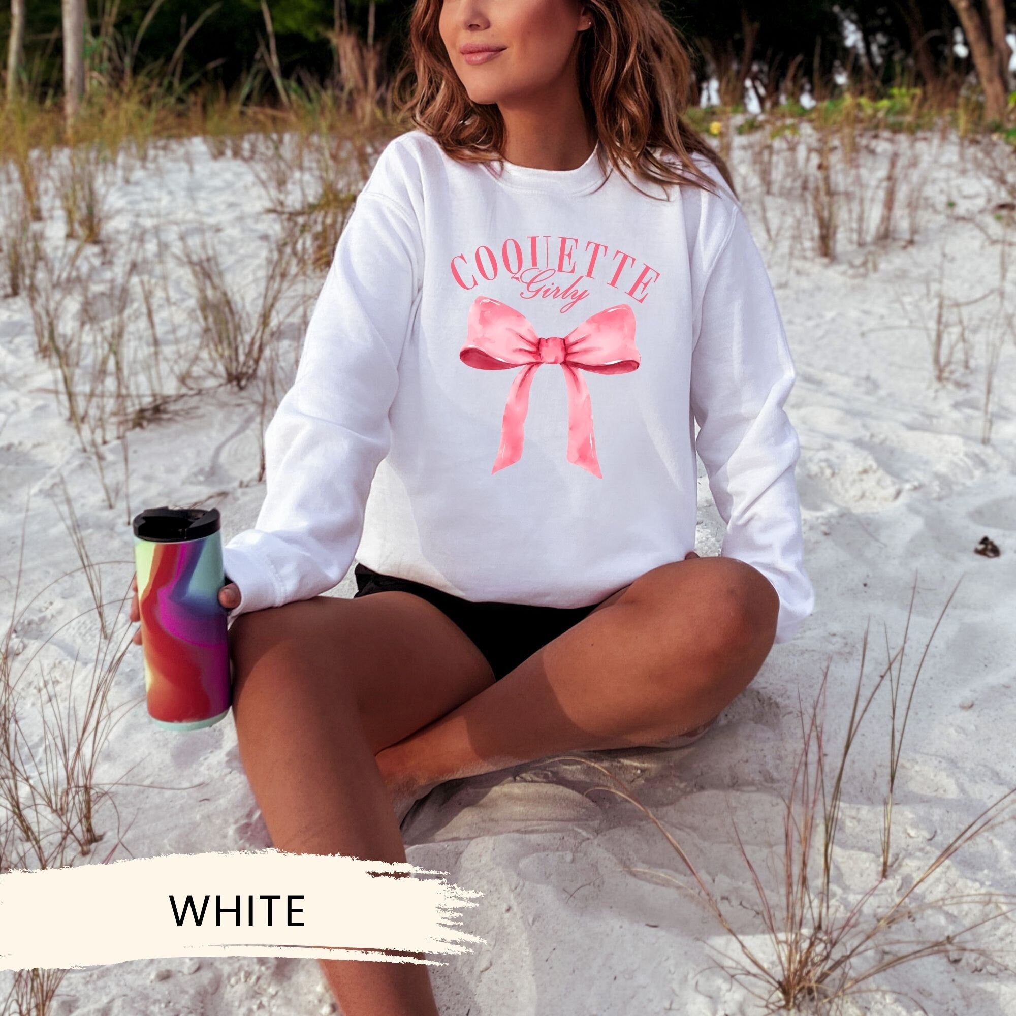 a woman sitting in the sand with a cup of coffee