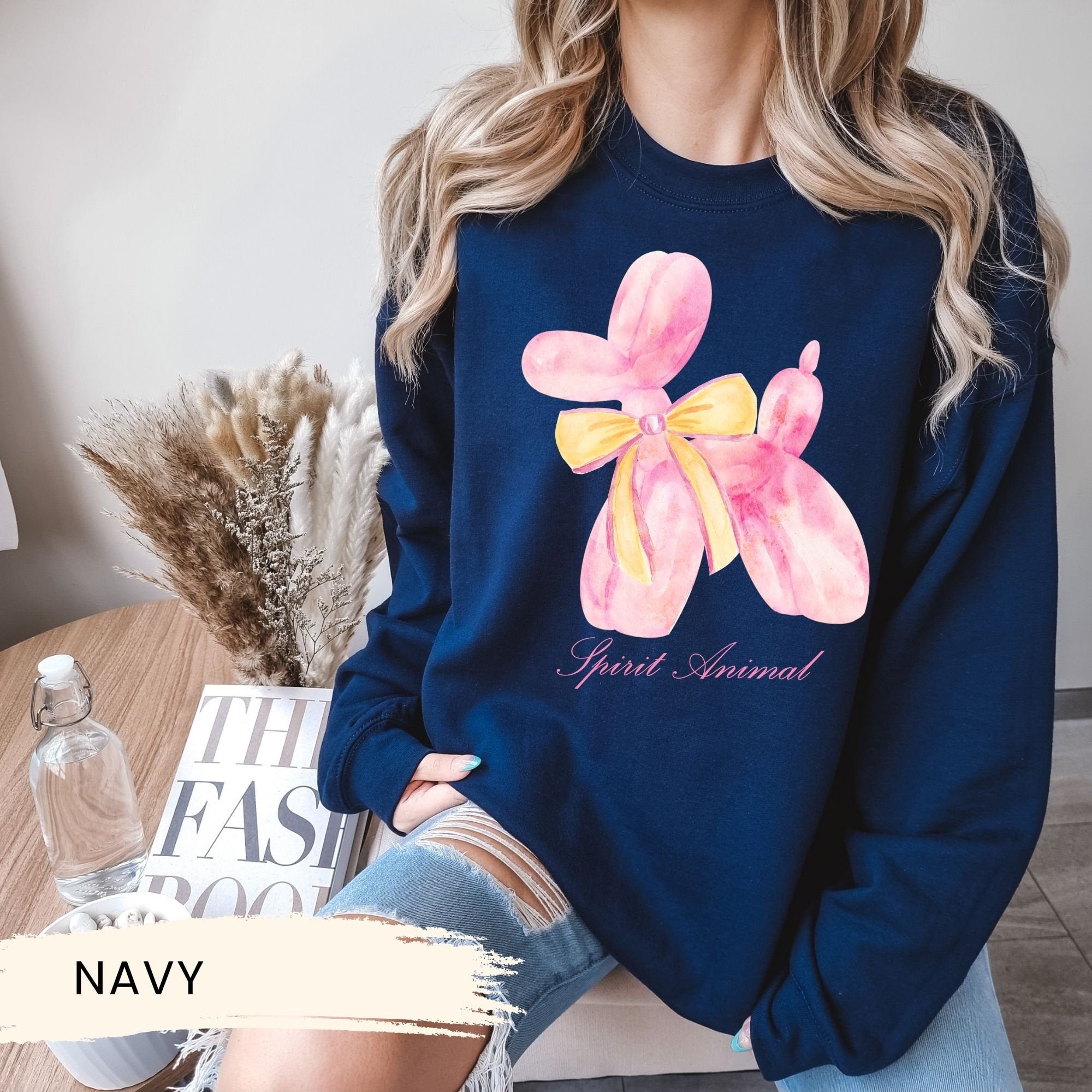 a woman wearing a navy sweatshirt with a pink flower on it