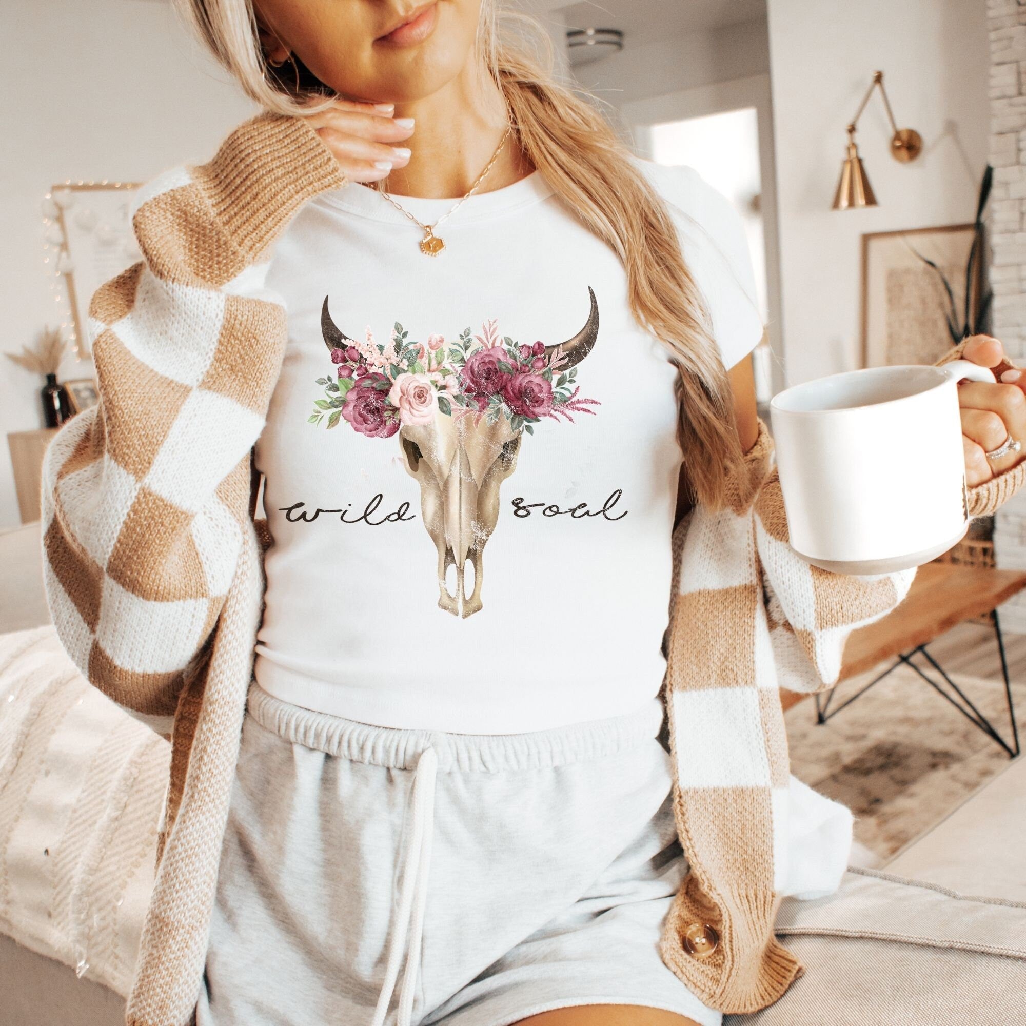a woman holding a cup of coffee and wearing a sweater