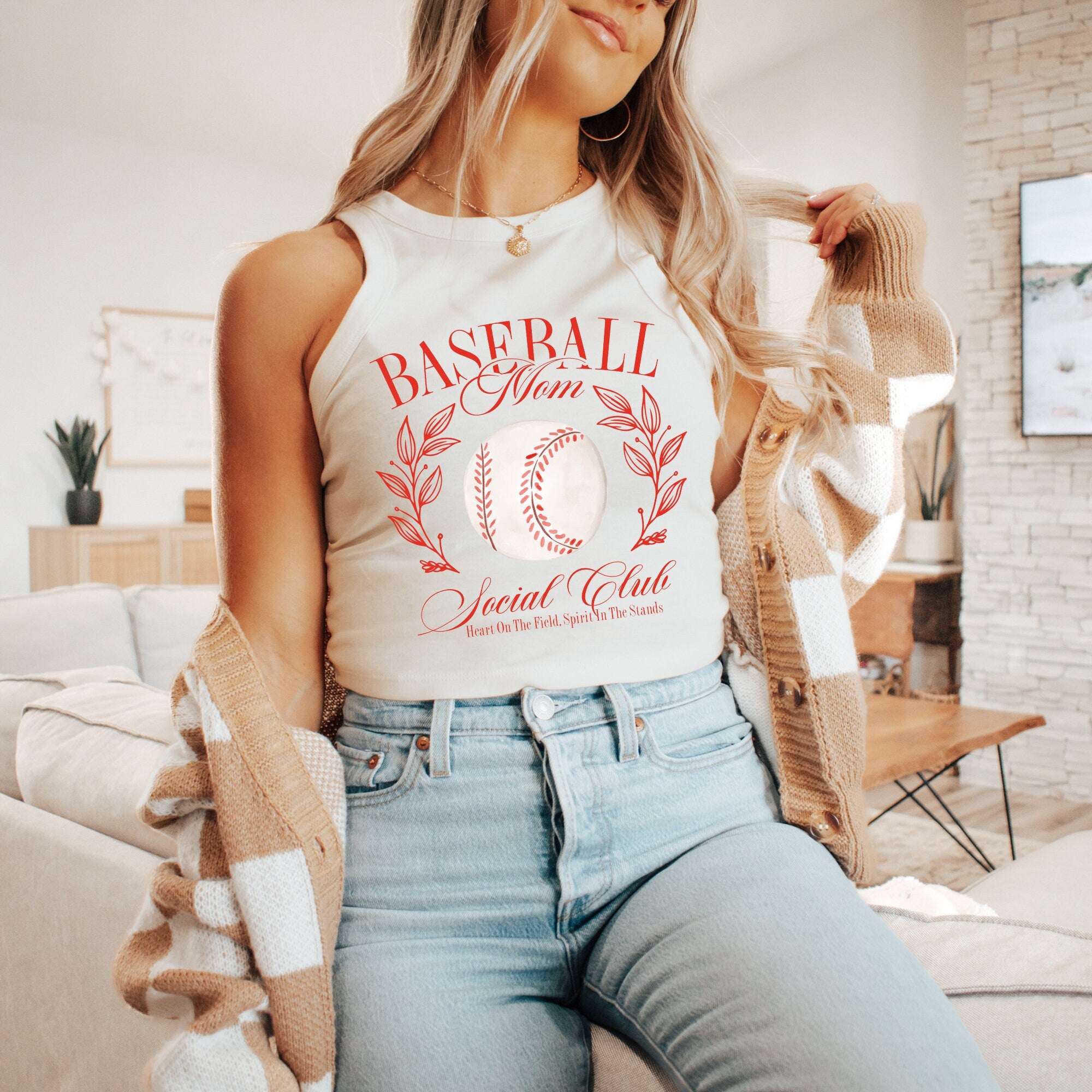 a woman sitting on a couch wearing a baseball tank top