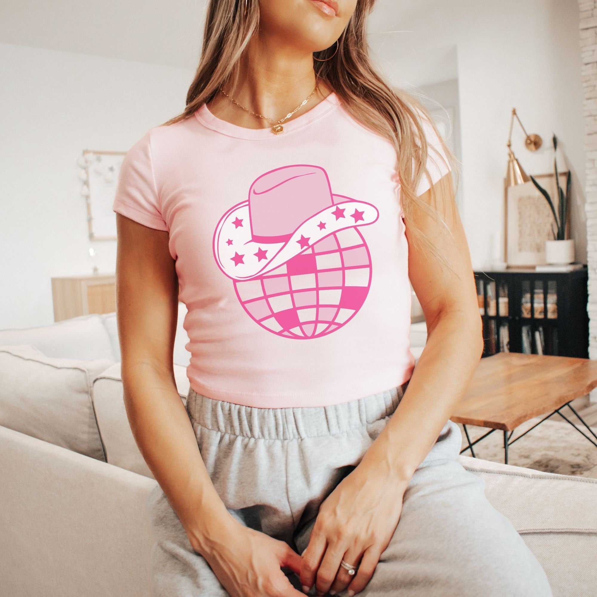 a woman sitting on a couch wearing a pink shirt