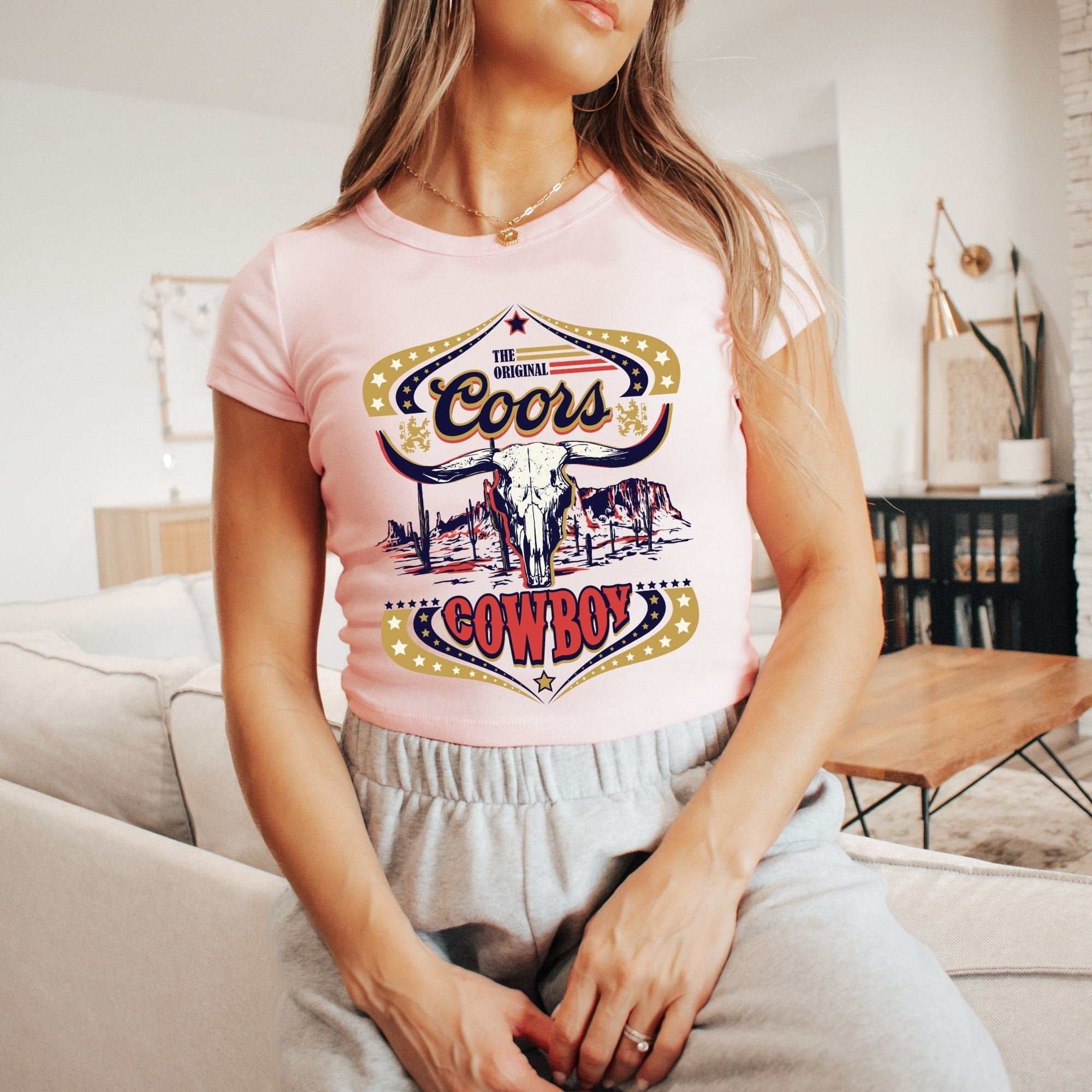 a woman sitting on a couch wearing a pink shirt