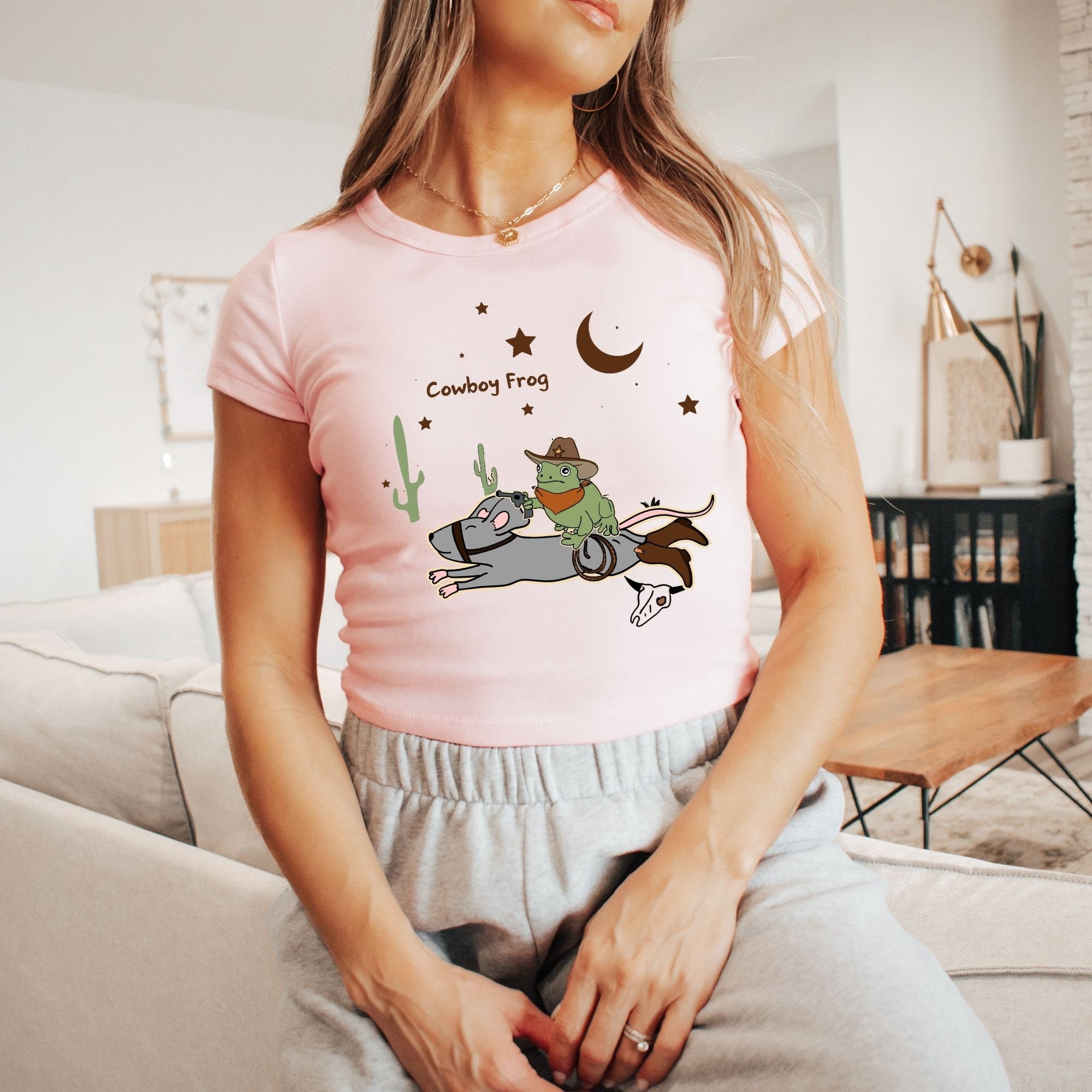 a woman sitting on a couch wearing a pink shirt