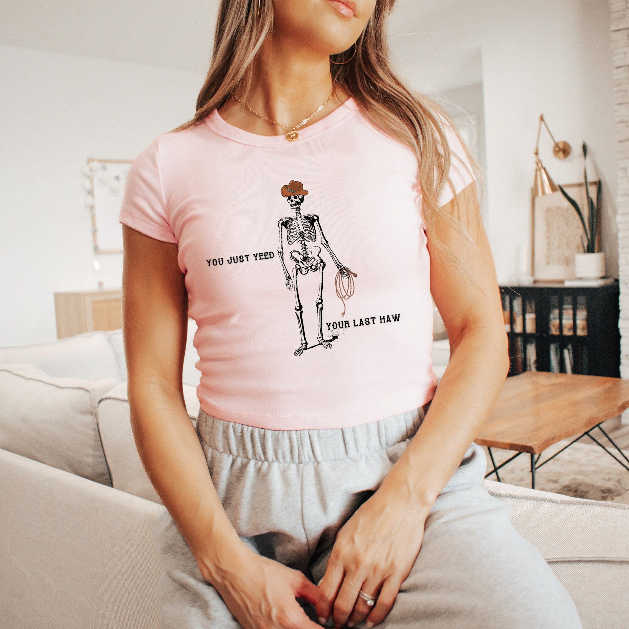 a woman sitting on a couch wearing a pink shirt
