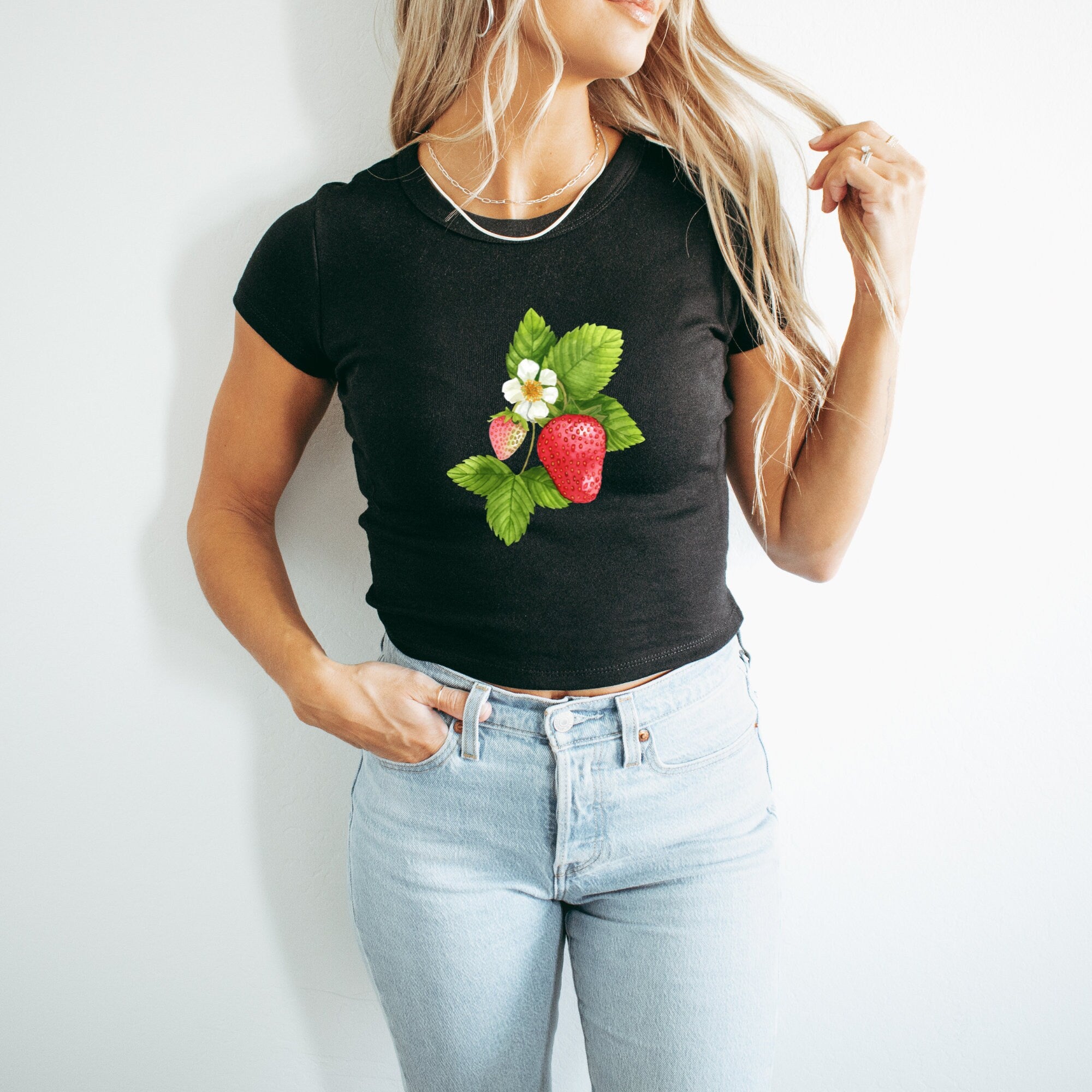a woman wearing a black shirt with a strawberry on it