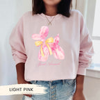 a woman wearing a pink sweatshirt with a yellow bow