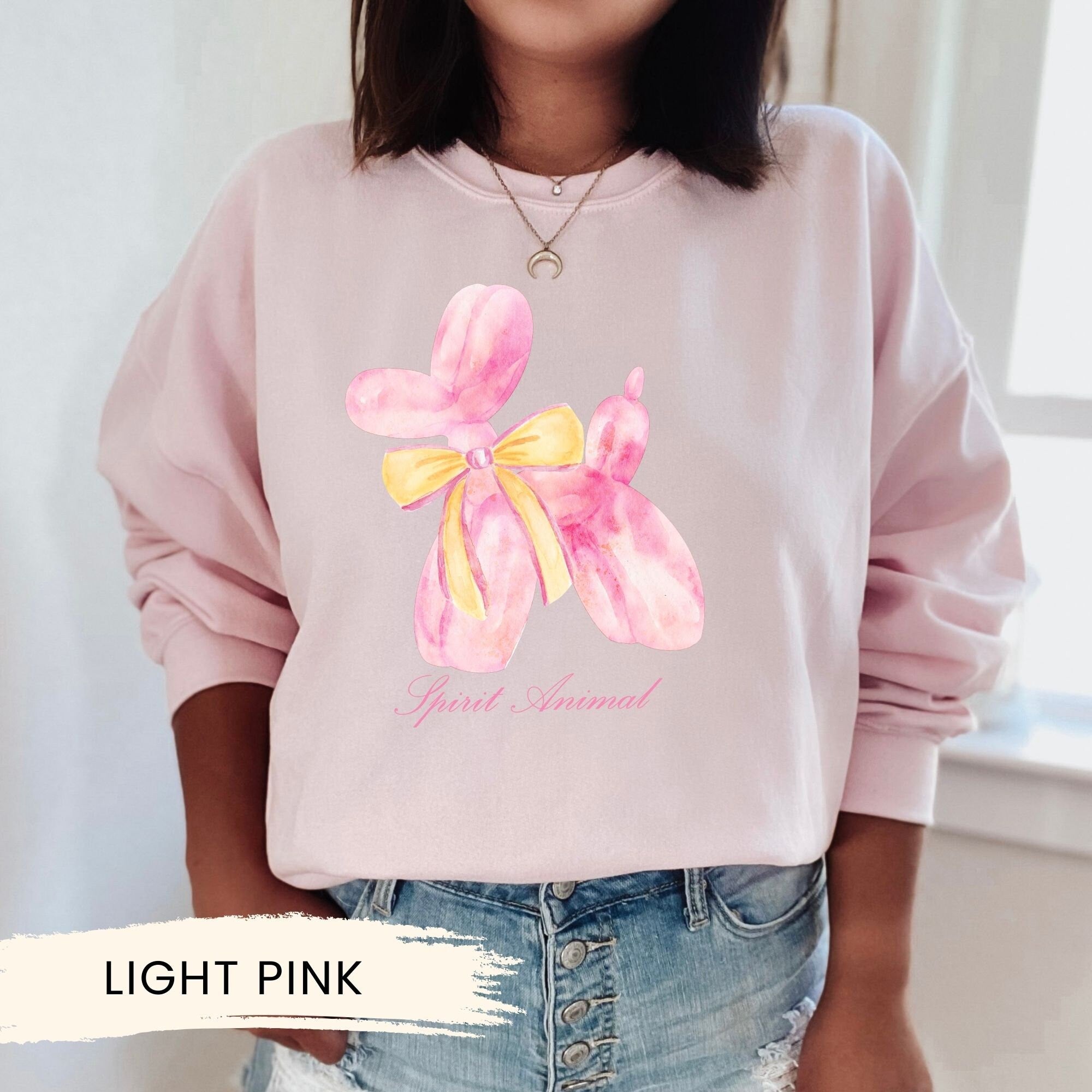 a woman wearing a pink sweatshirt with a yellow bow