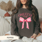 a woman wearing a sweatshirt with a pink bow on it