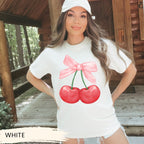 a woman wearing a white shirt with a pink bow and two cherries on it