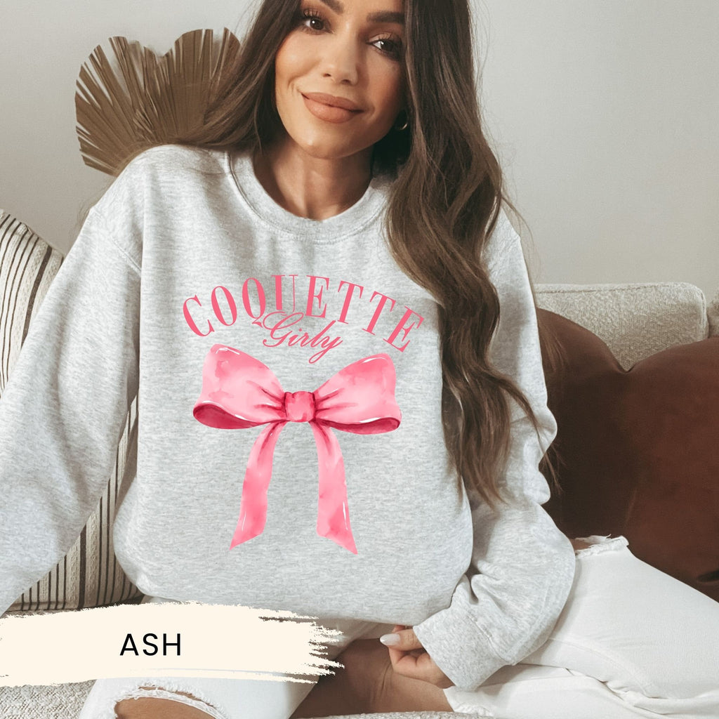 a woman sitting on a couch wearing a sweatshirt with a pink bow