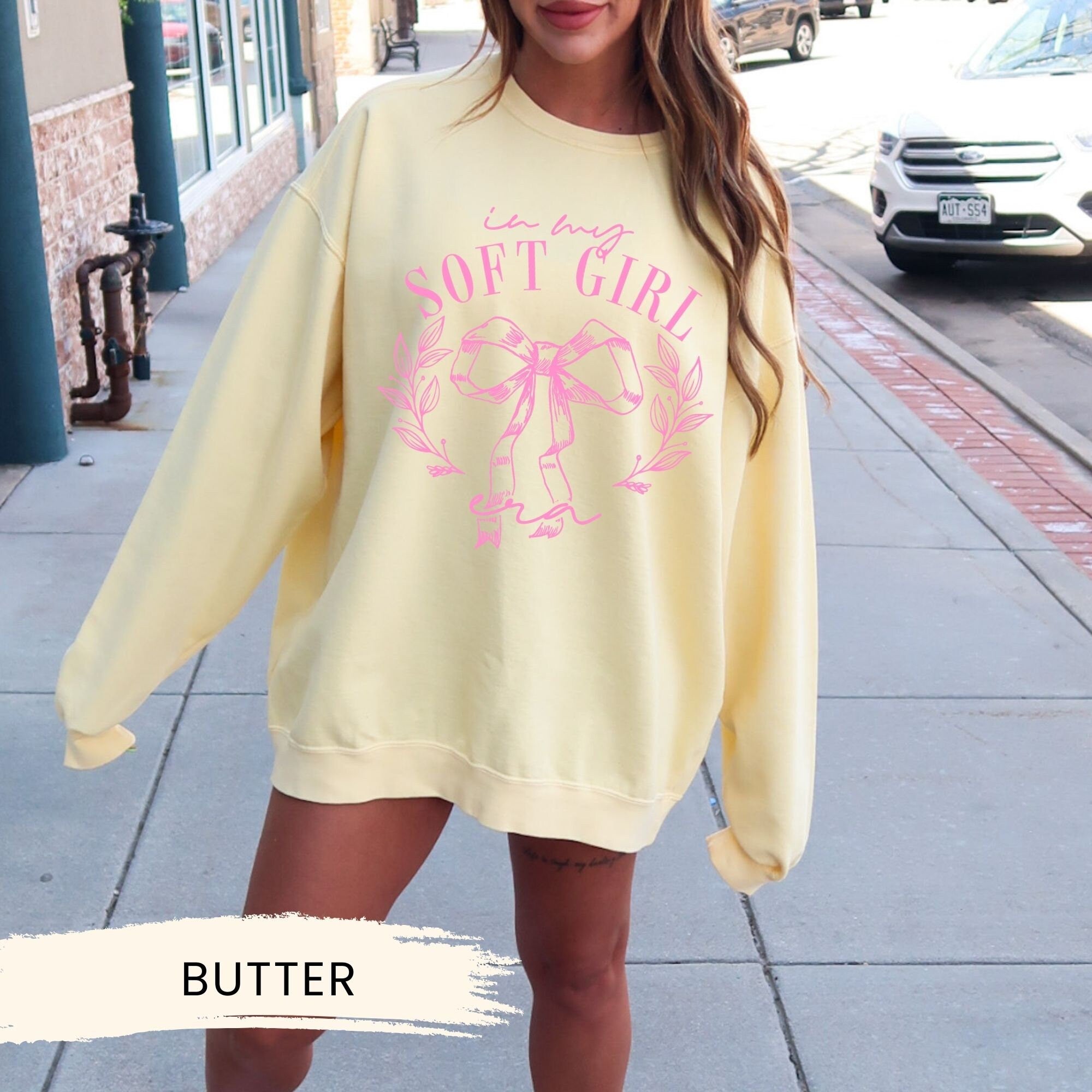 a woman is standing on a sidewalk wearing a yellow sweatshirt