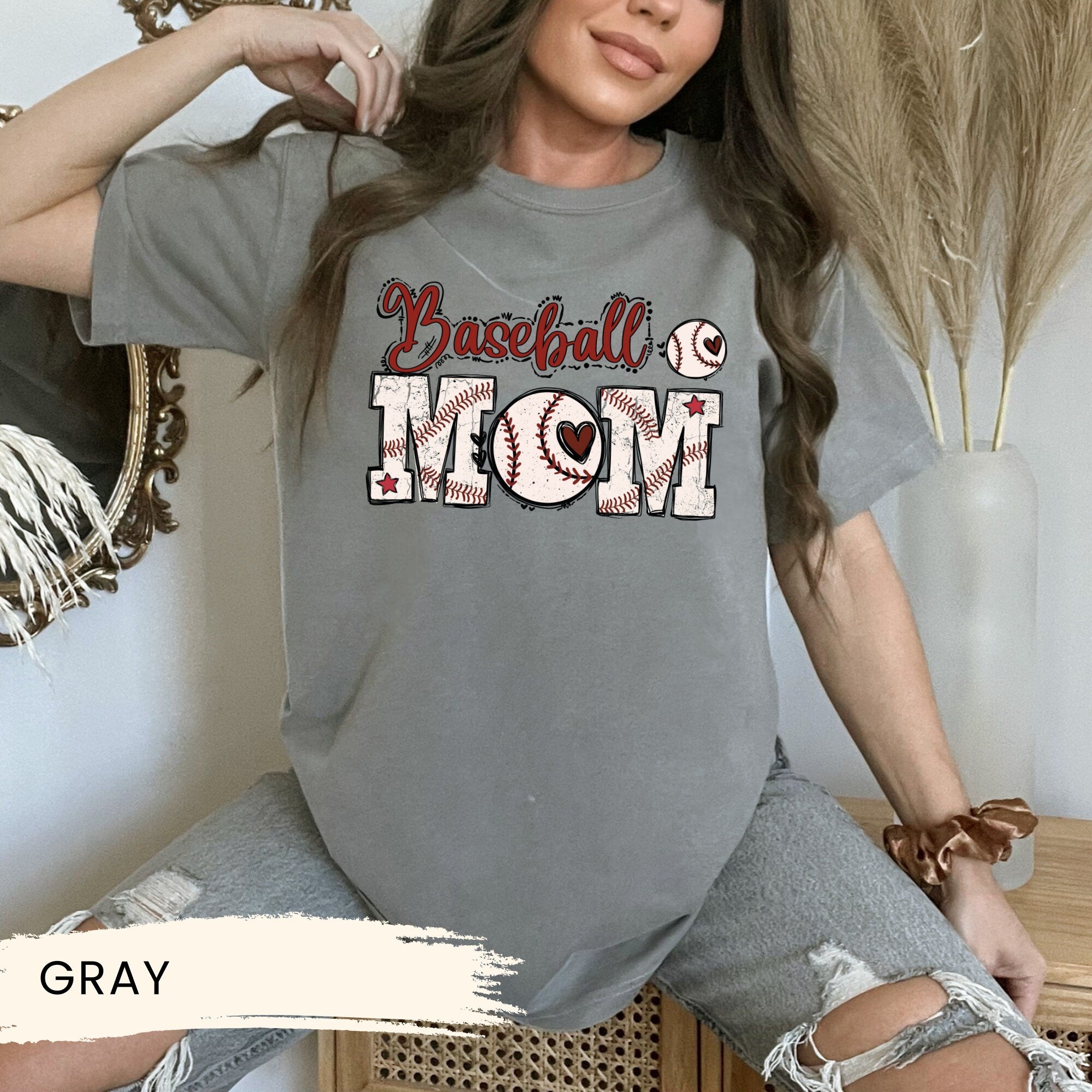 a woman sitting on a chair wearing a baseball mom shirt