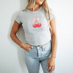 a woman wearing a grey shirt with a cherry on it