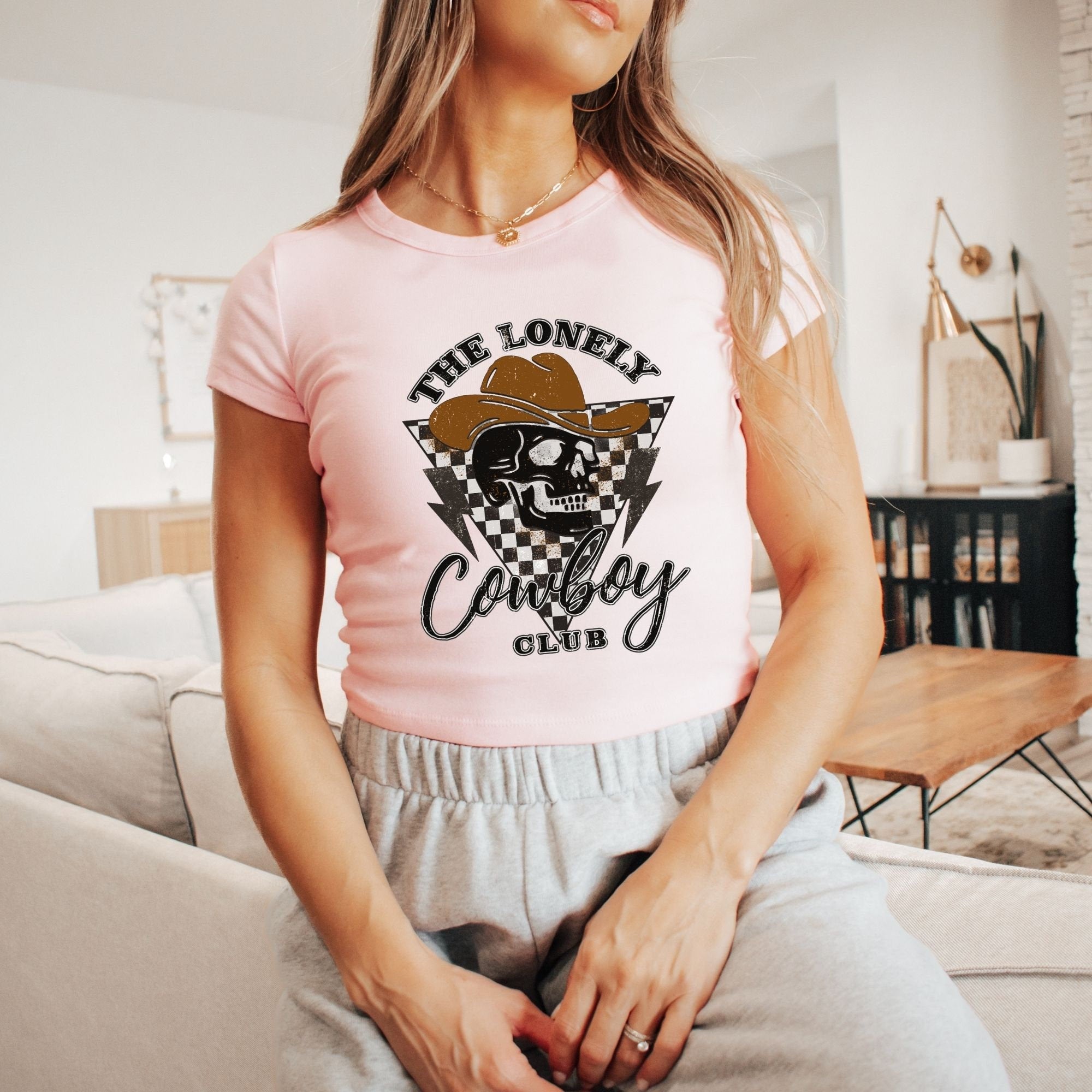 a woman sitting on a couch wearing a pink shirt