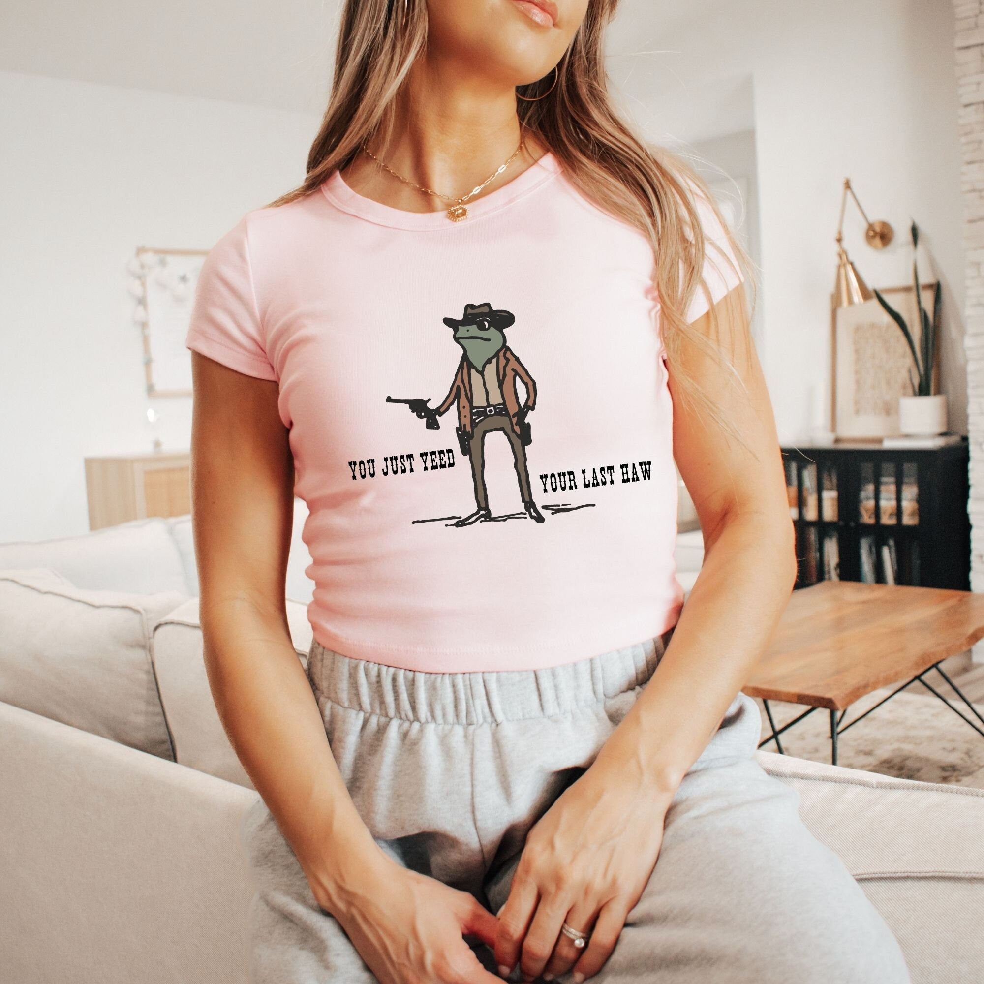 a woman sitting on a couch wearing a pink shirt