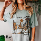 a woman wearing a t - shirt with an image of a cowboy riding a horse