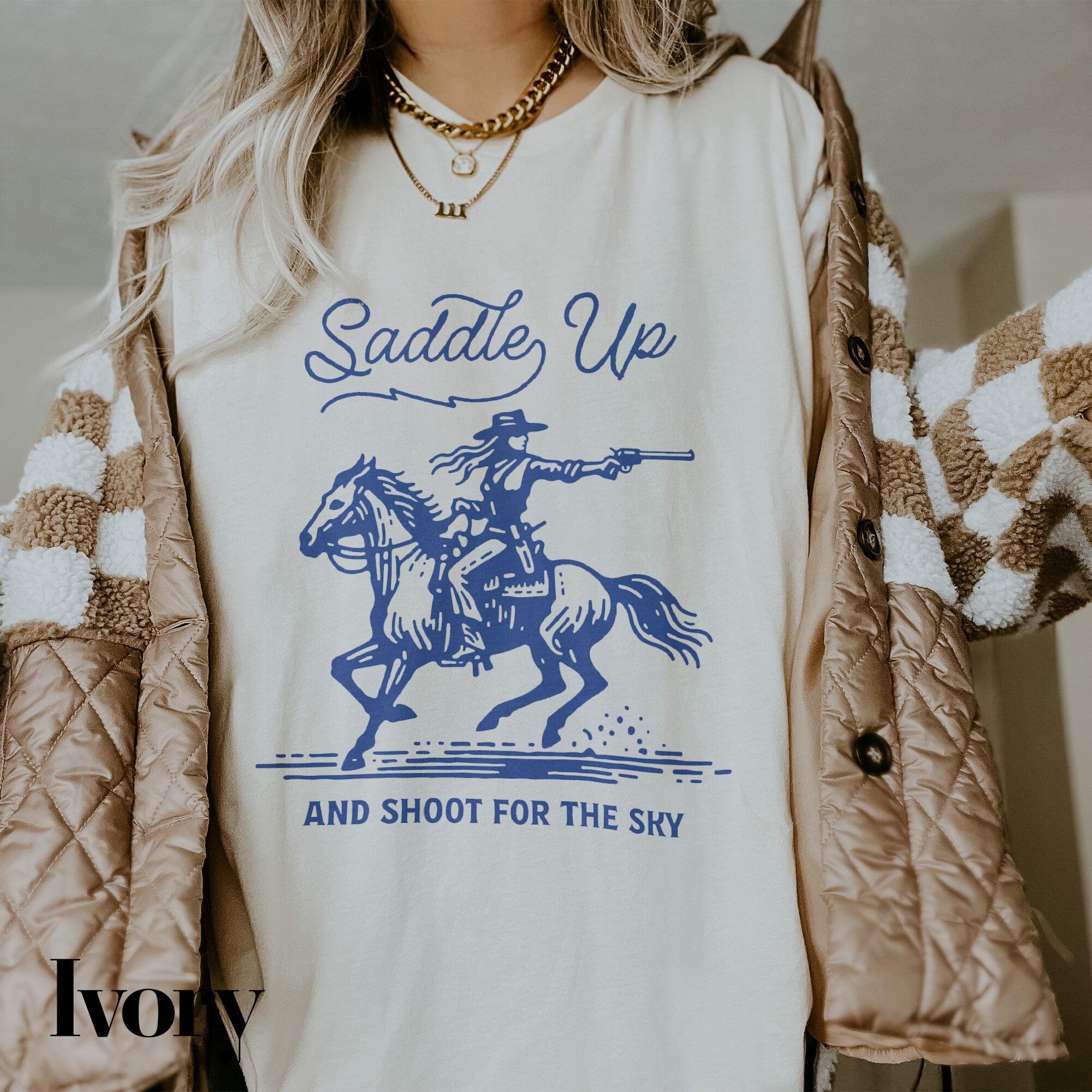 a woman wearing a t - shirt with a picture of a cowboy riding a horse