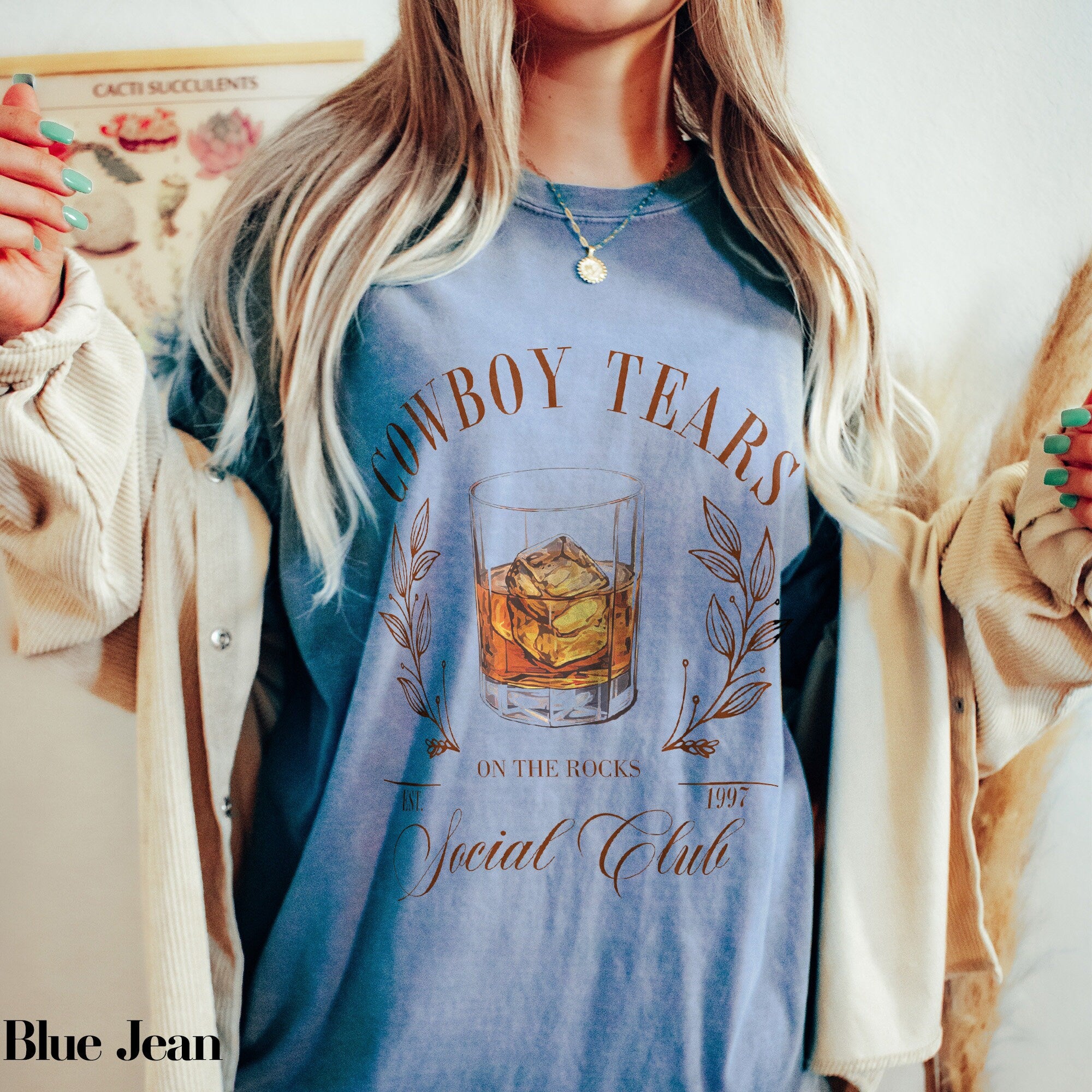 a woman wearing a blue shirt with a glass of whiskey on it