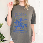 a woman wearing a t - shirt with a picture of a man riding a horse
