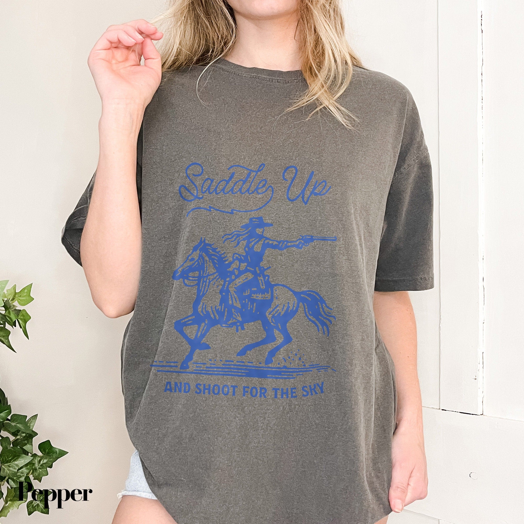a woman wearing a t - shirt with a picture of a man riding a horse