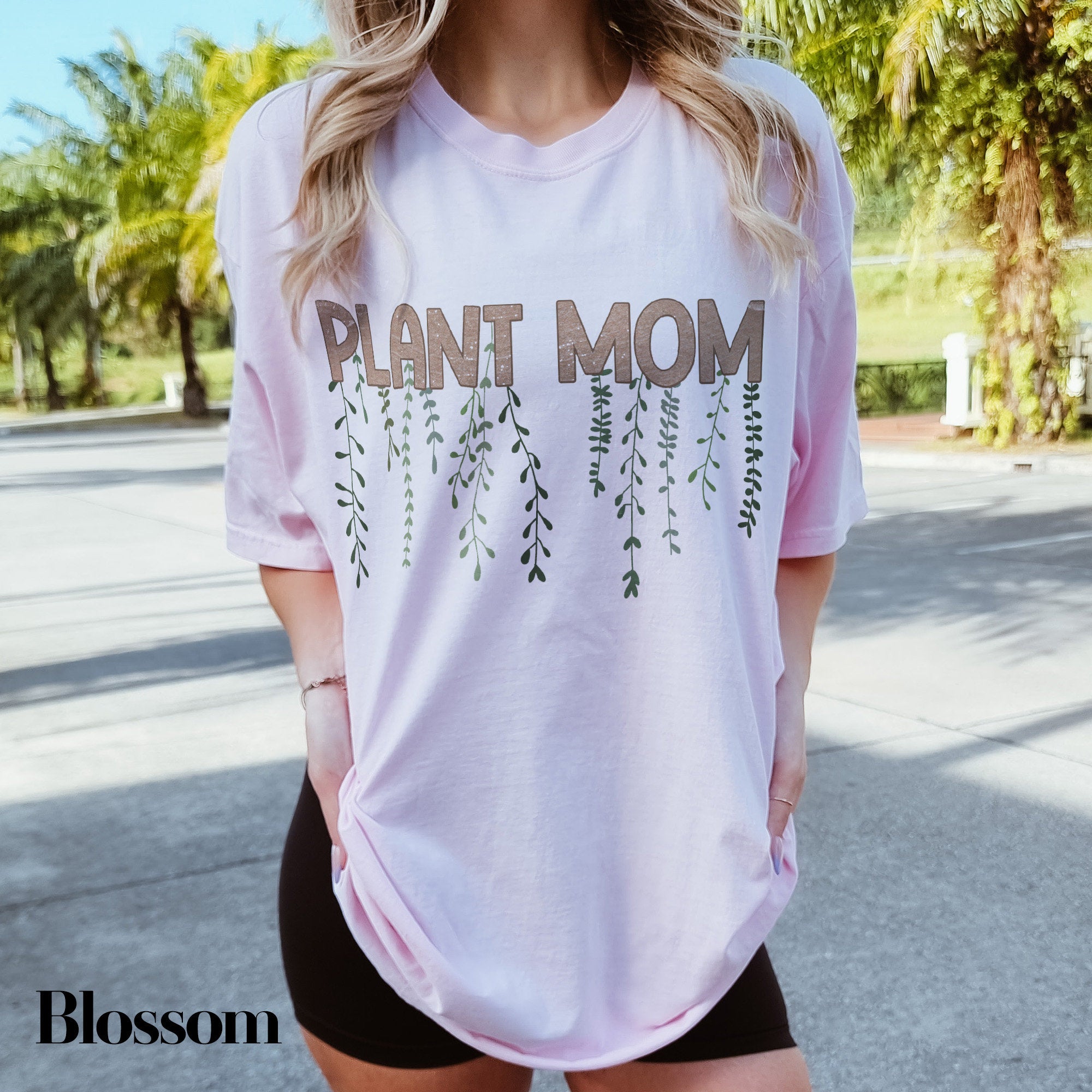 a woman wearing a pink shirt that says plant mom