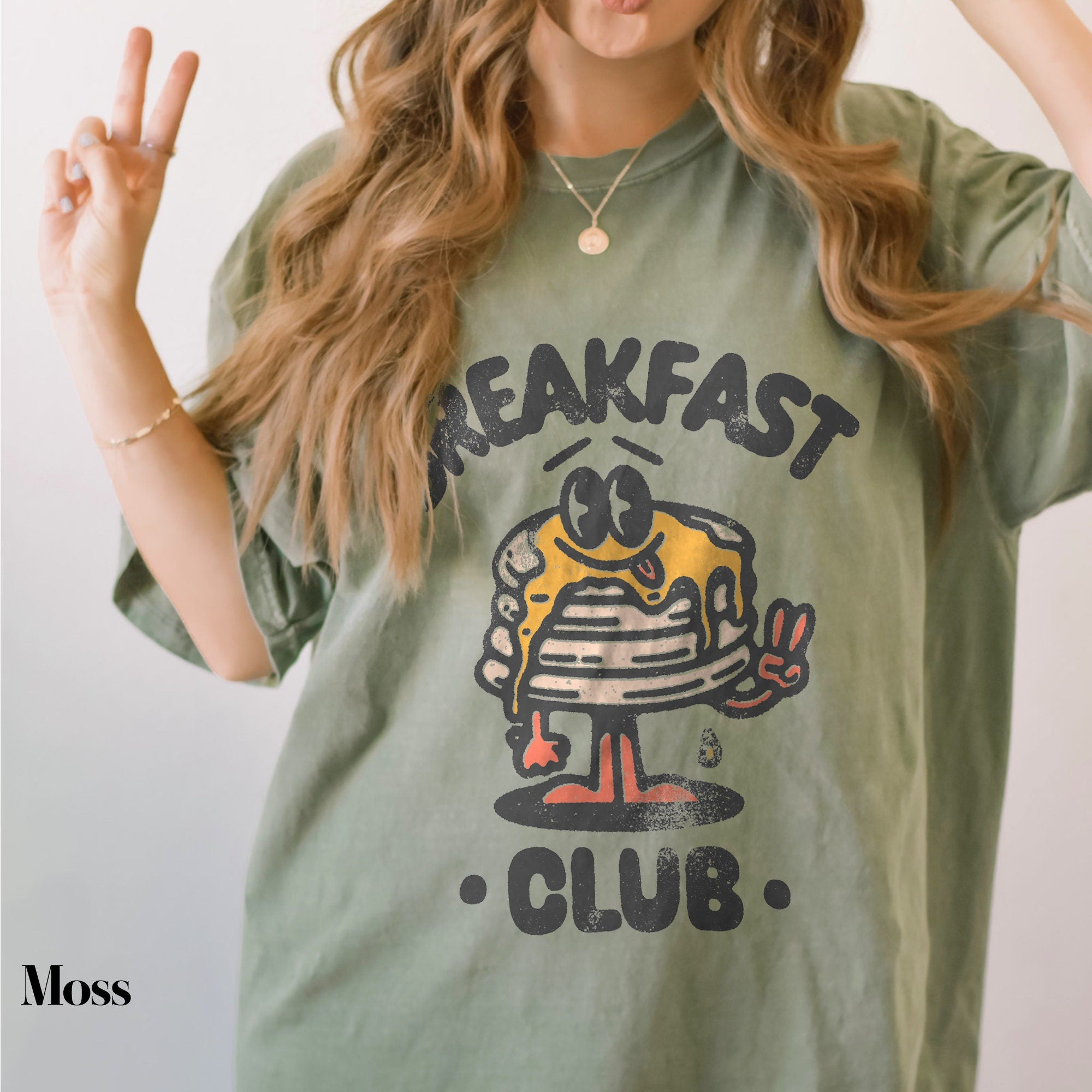 a woman wearing a green breakfast club shirt