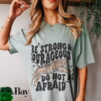 a woman wearing a t - shirt that says be strong and courageous
