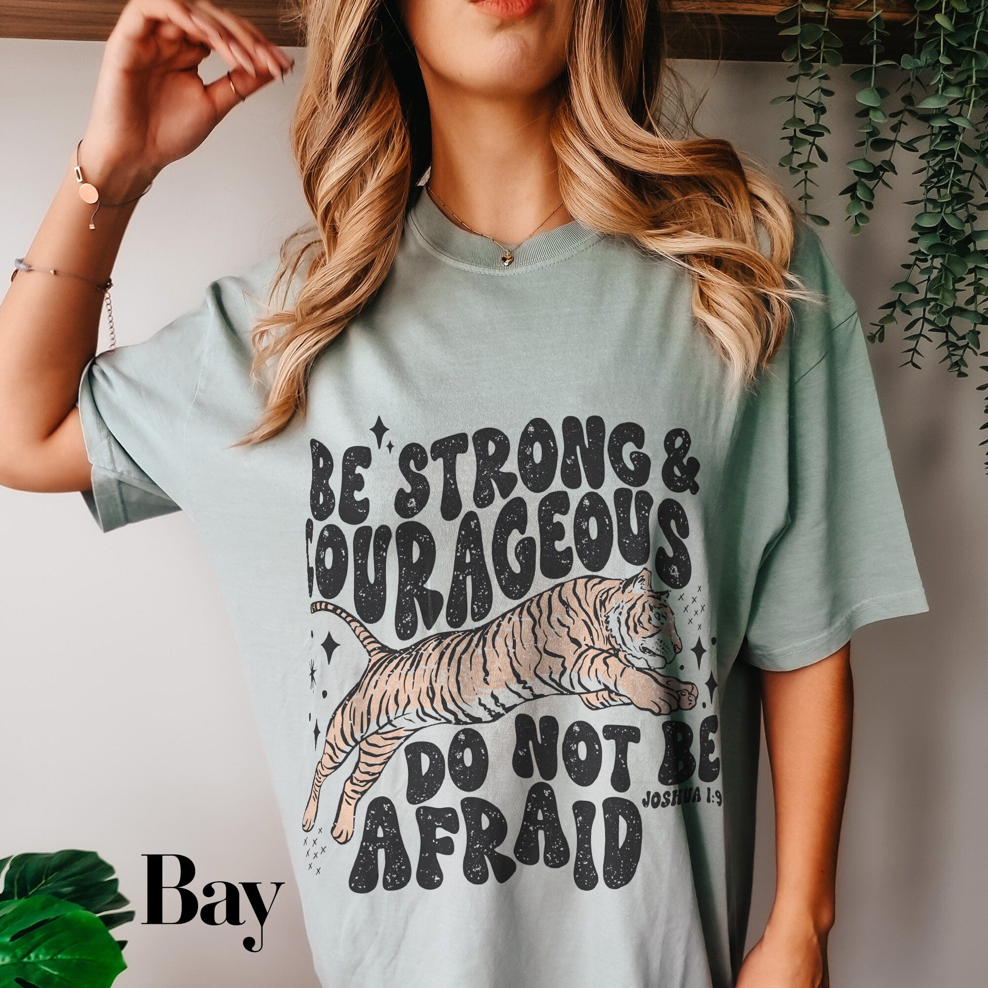 a woman wearing a t - shirt that says be strong and courageous