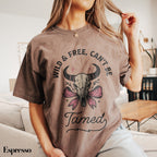 a woman sitting on a couch wearing a t - shirt that says wild and free
