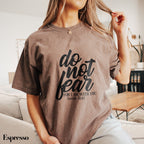 a woman sitting on a couch wearing a t - shirt that says do not fear