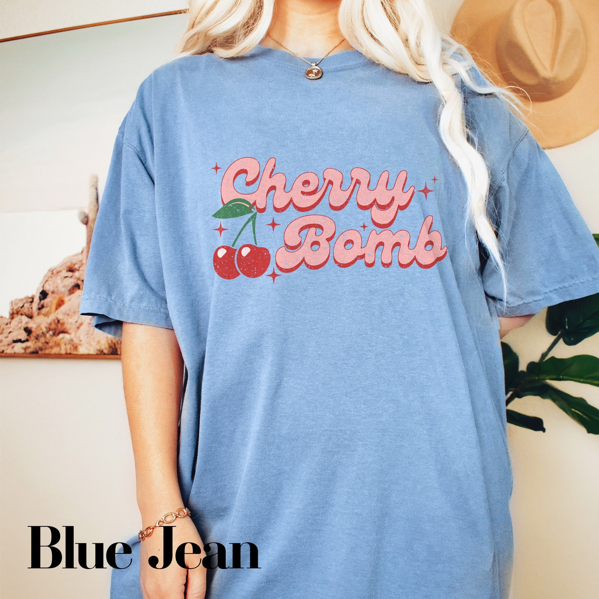 a woman wearing a blue cherry bomb t - shirt