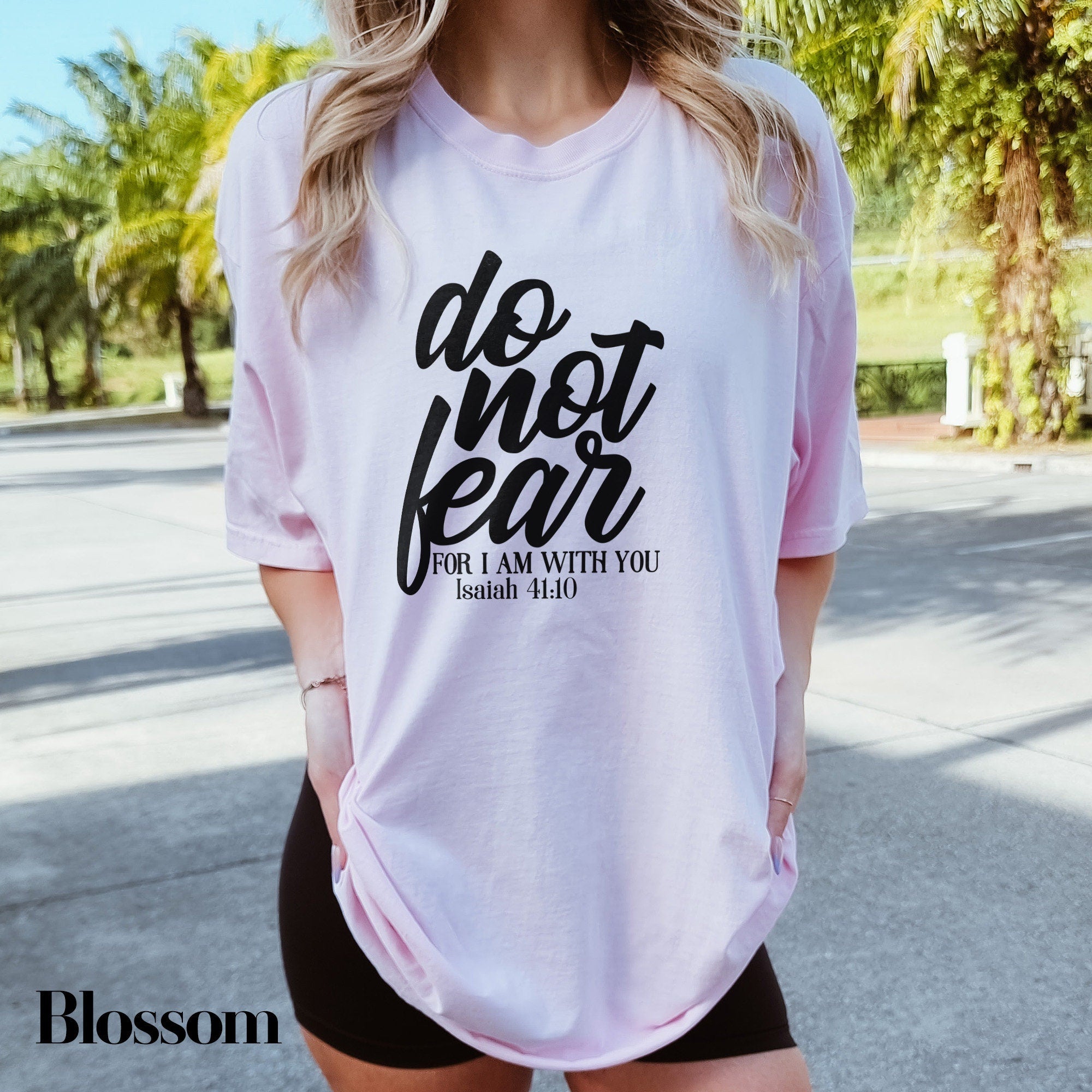 a woman wearing a pink shirt that says do not fear for i am with you